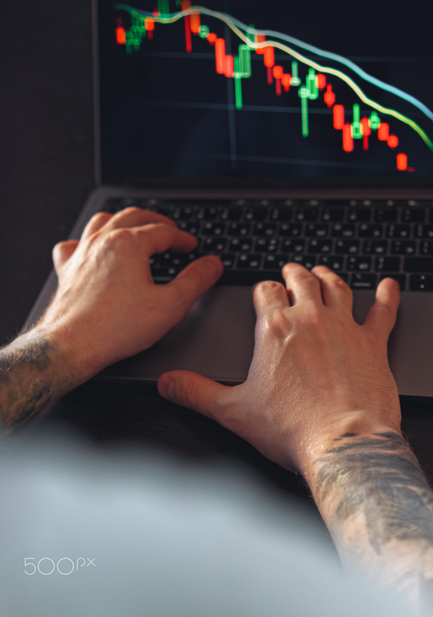 Male hands monitoring stock market numbers and graph on laptop