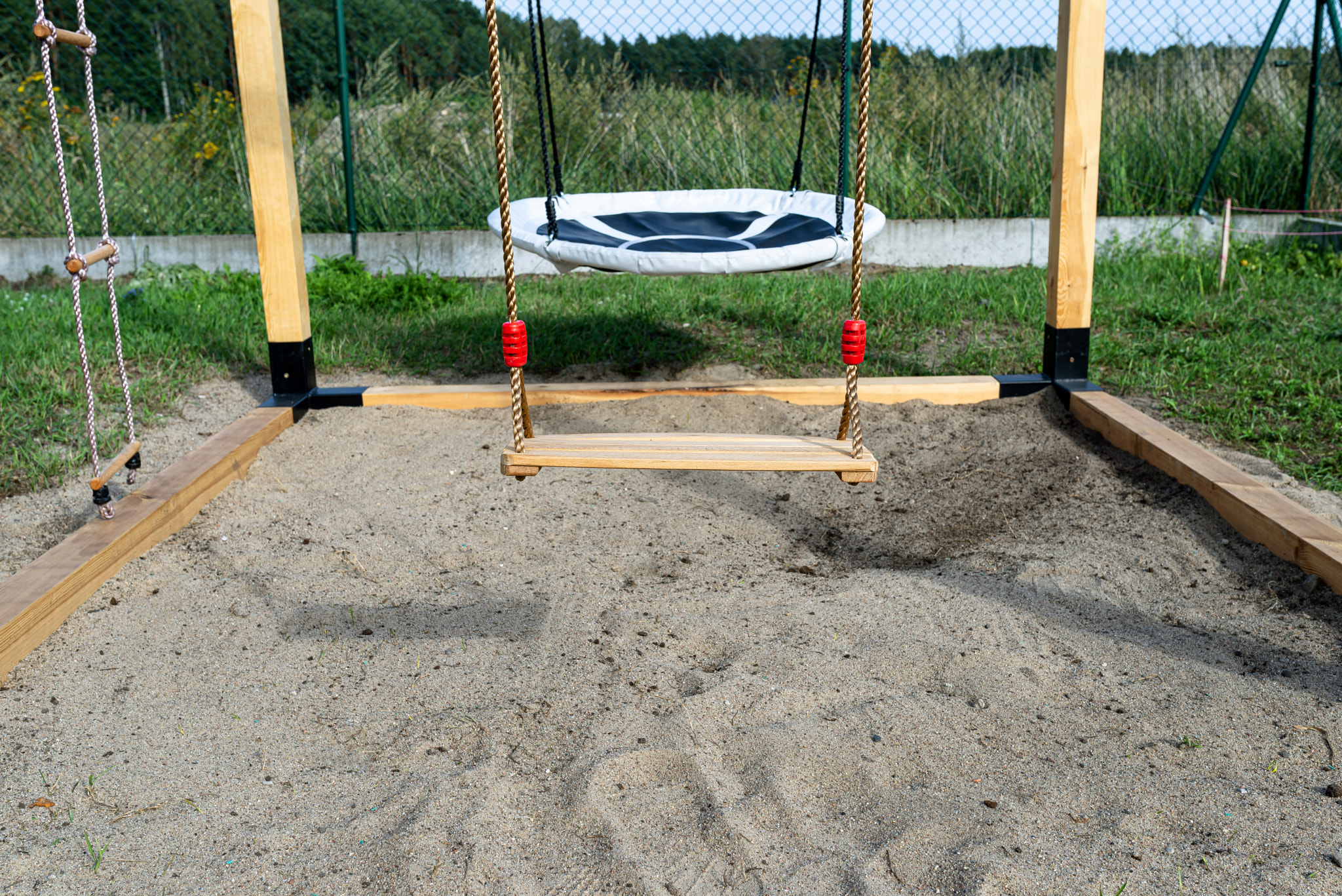 A modern cubic playground made of wooden logs and metal corners, a visible rocker and a nest.