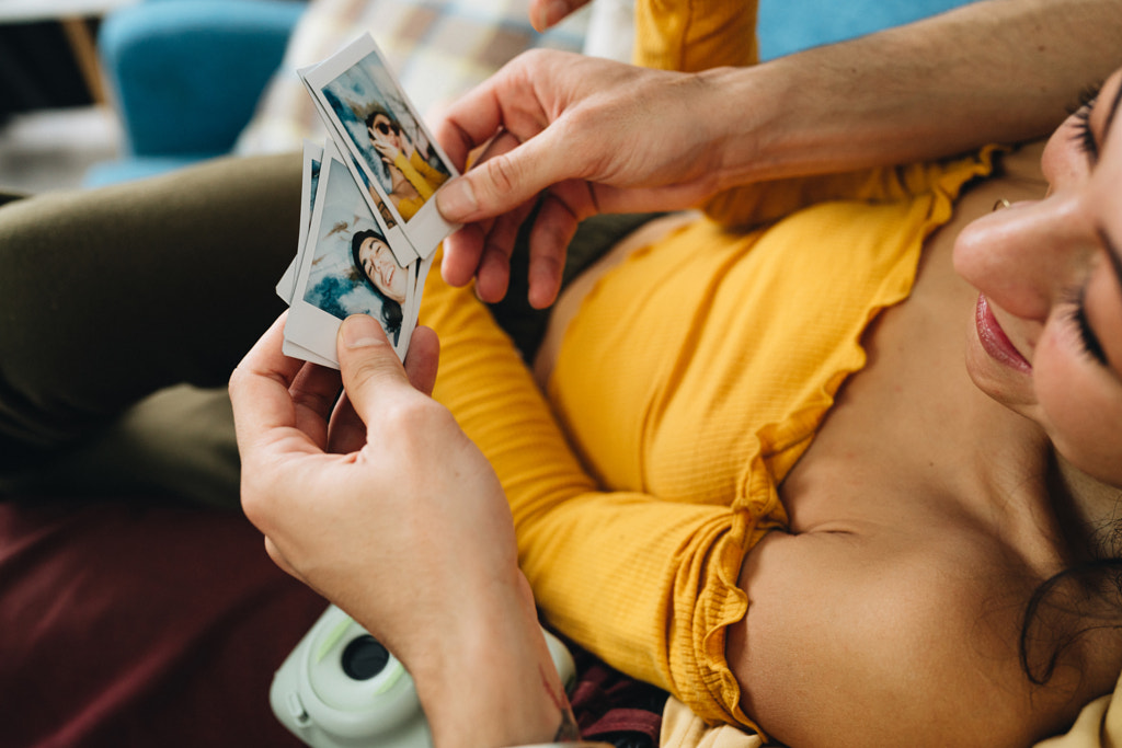 Happy couple relaxing on sofa at home and looking at the pictures by Natalie Zotova on 500px.com