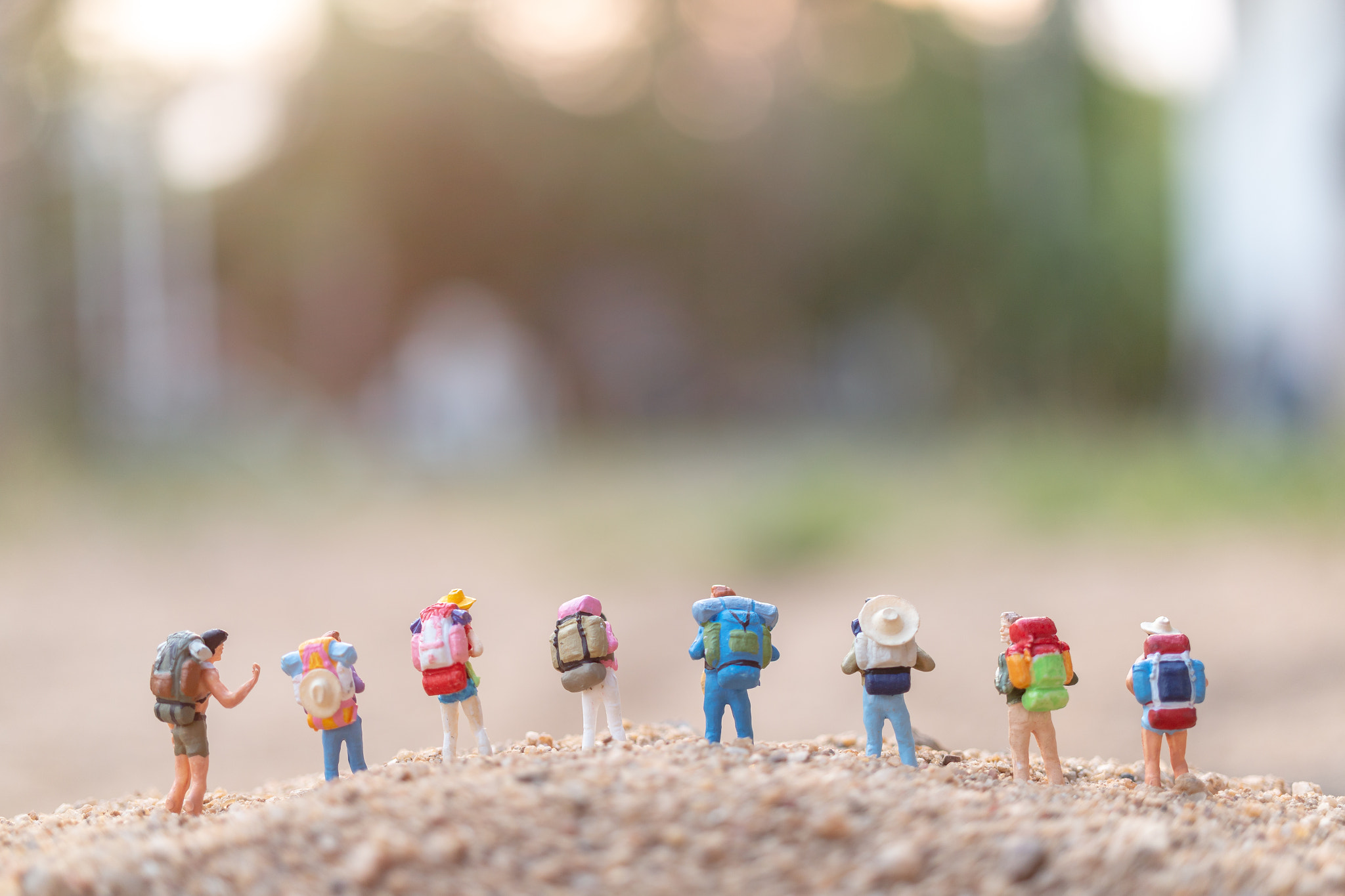 Miniature people : Traveler with backpack walking on sand