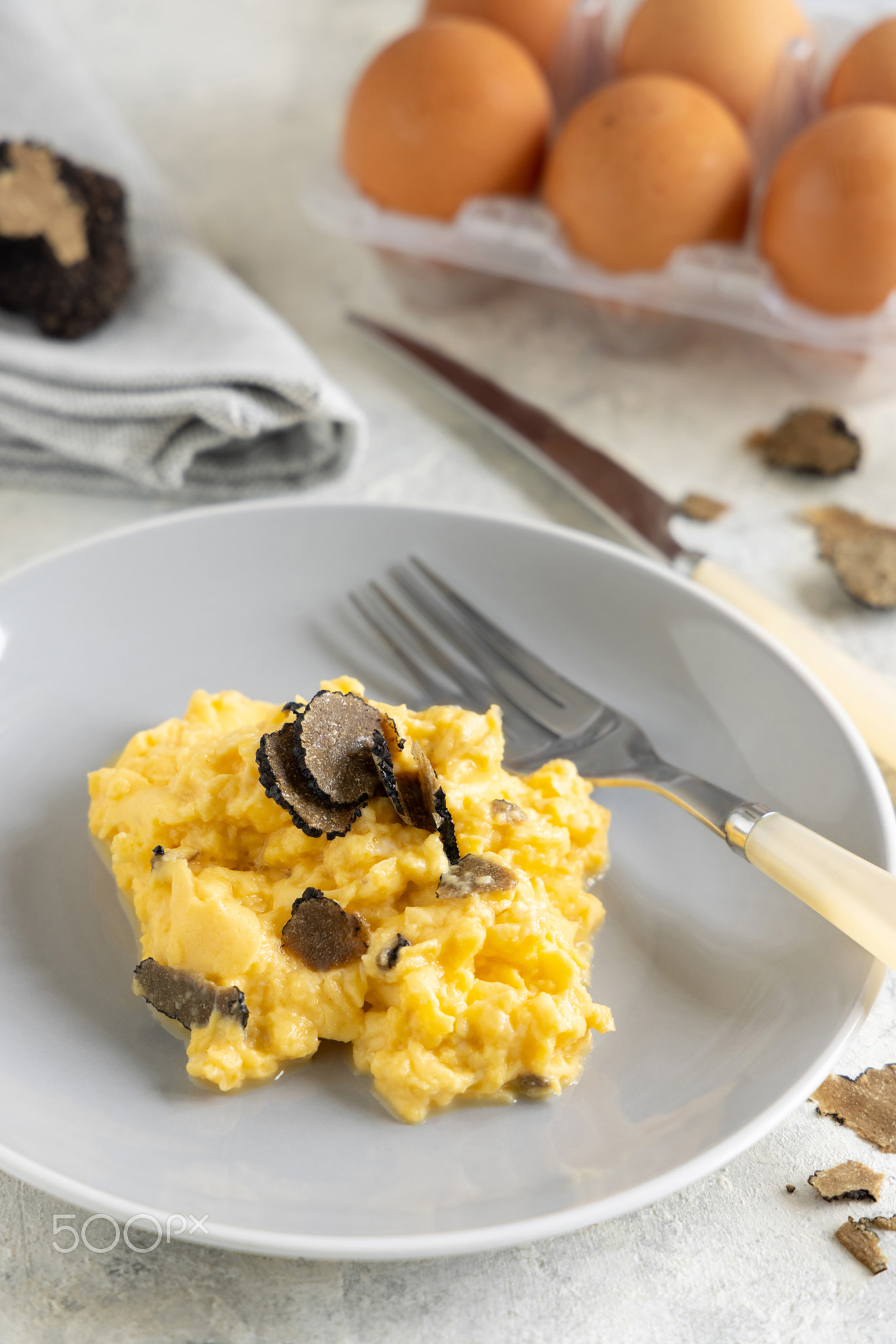 Scrambled eggs with fresh black truffles from Italy served in a plate close up, gourmet breakfast