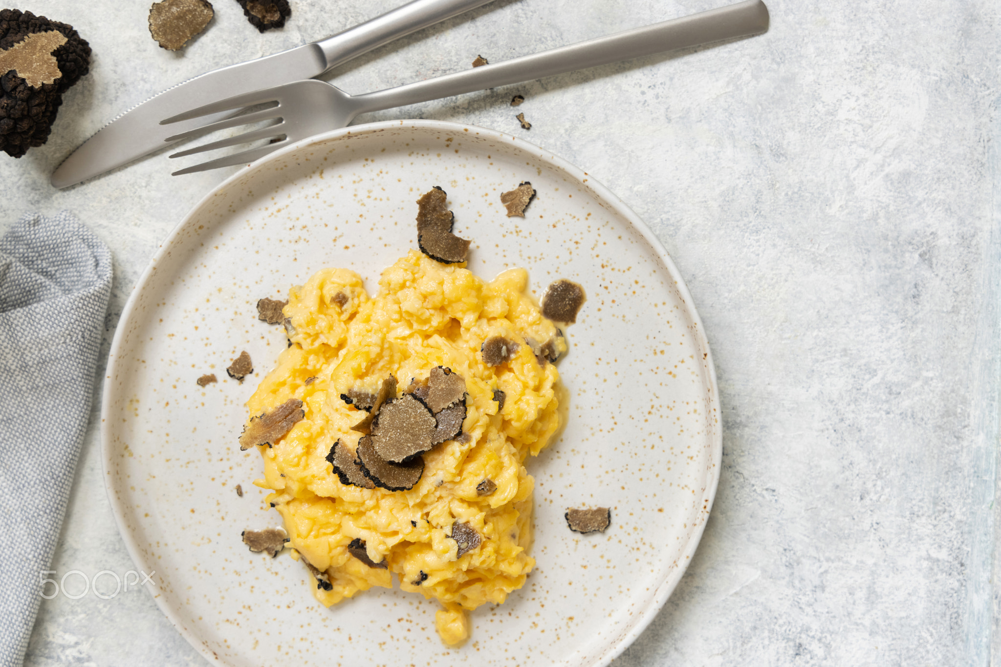 Scrambled eggs with fresh black truffles from Italy served in a plate top view, gourmet breakfast