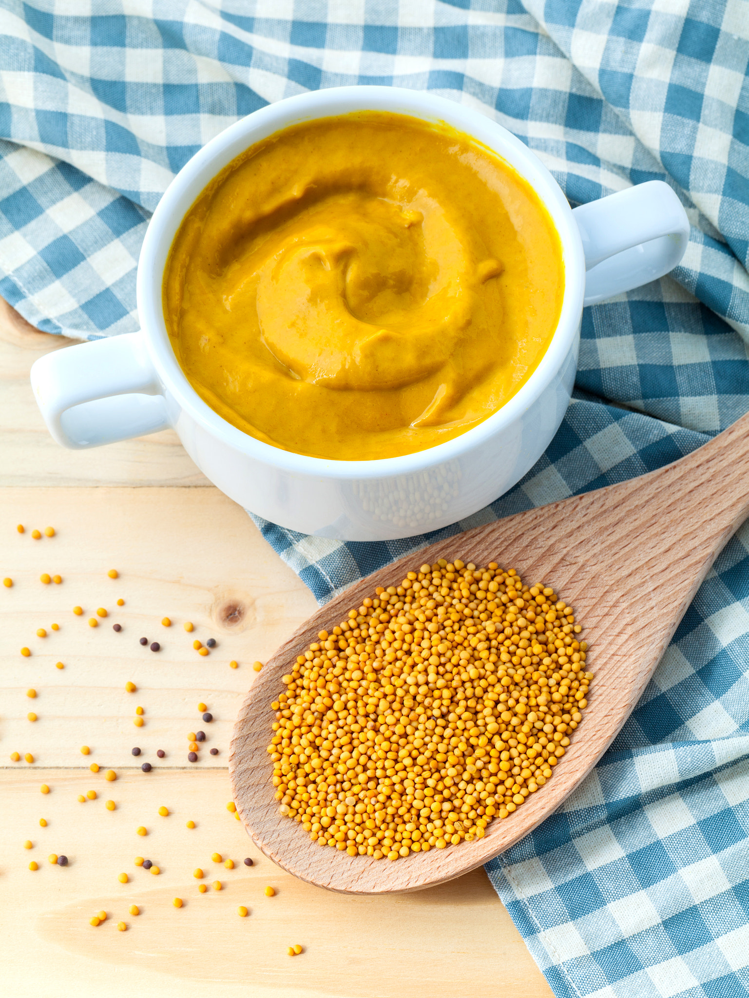 Composition of mustard and mustard seeds on wooden background.