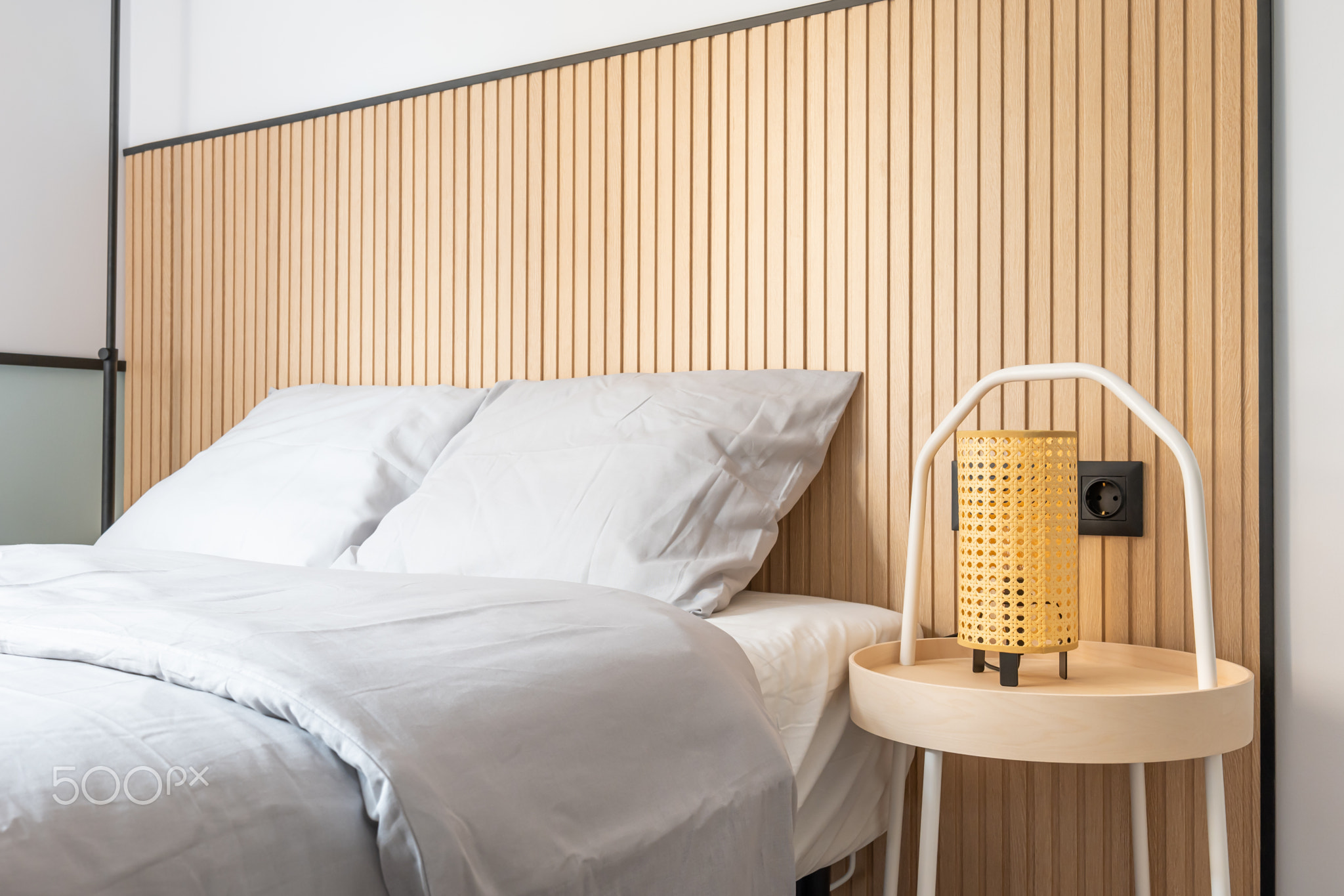 Closeup of a bedroom with a double bed against a white wall with