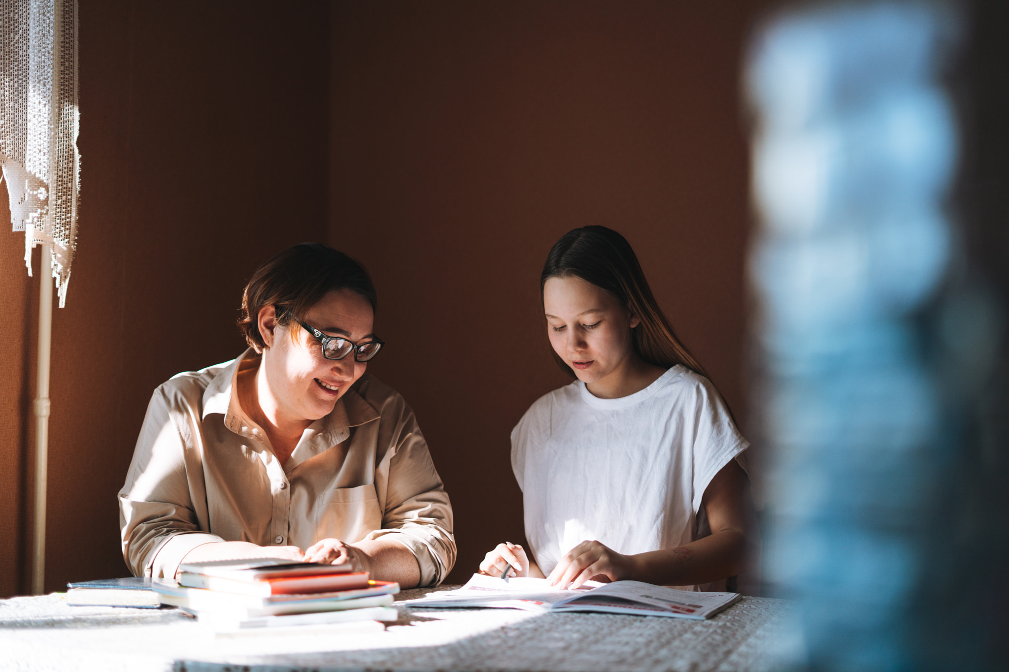 Teenage girl doing homework with her mother in room at home