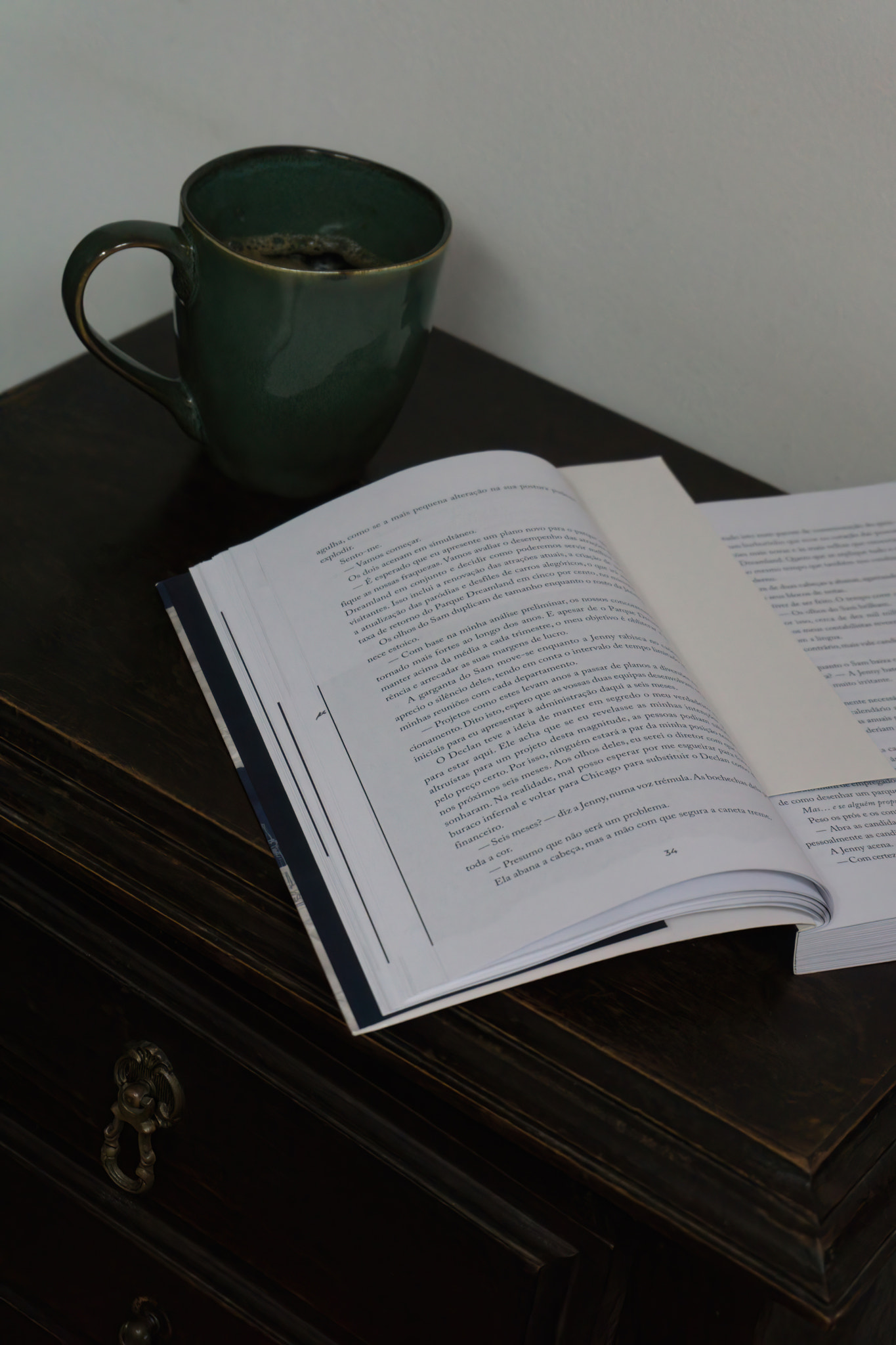 Open book and coffee cup on bedside table