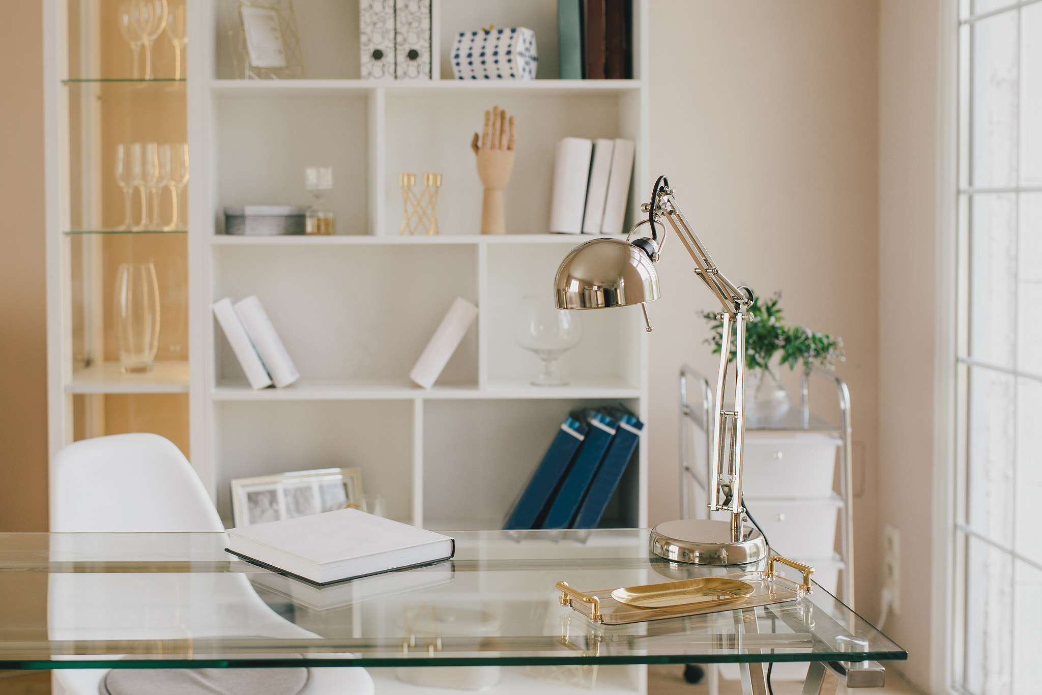 Light-colored workplace with a desk lamp and a bookcase