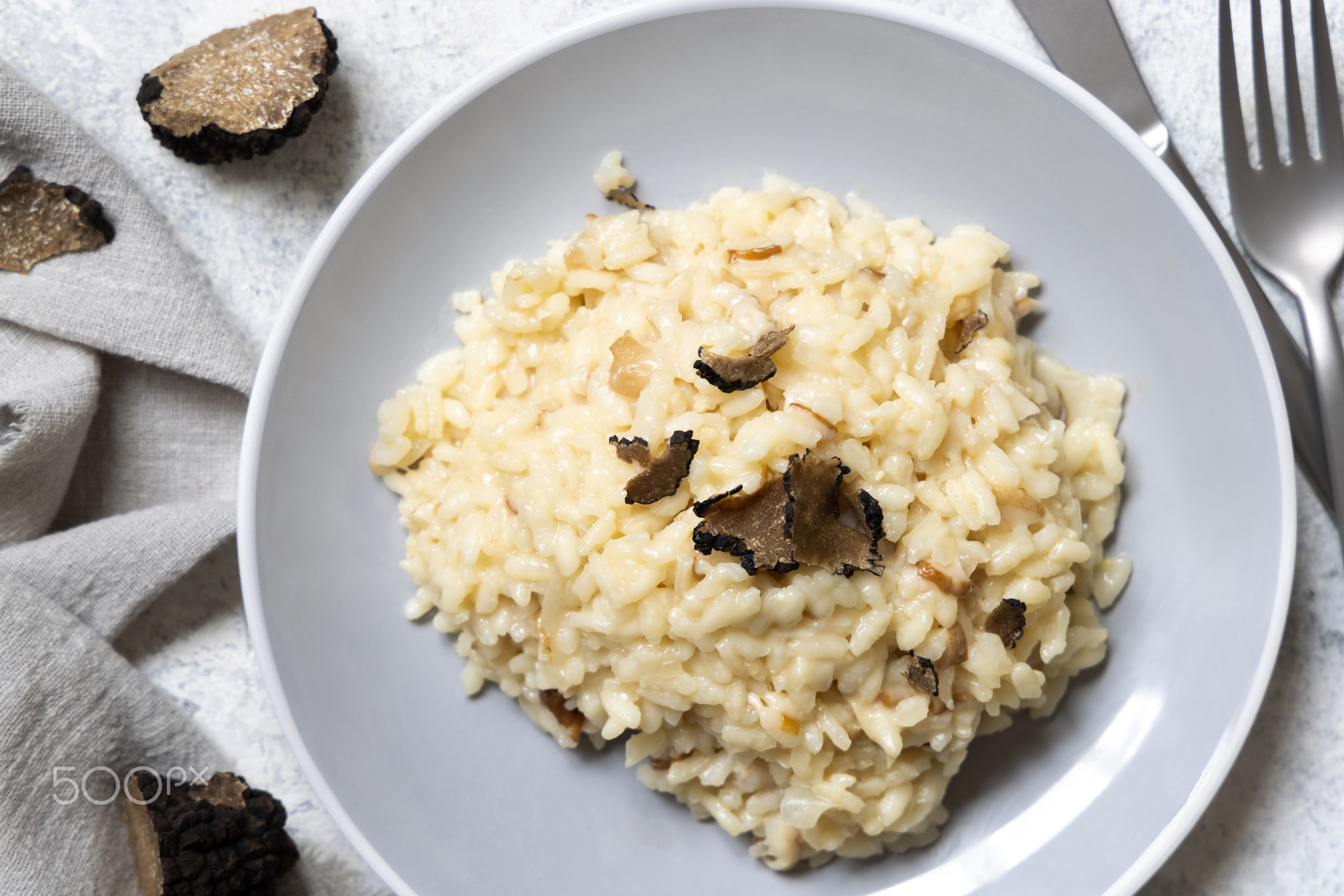 Risotto with porcini mushrooms and black truffles served in a plate top view, gourmet cousine