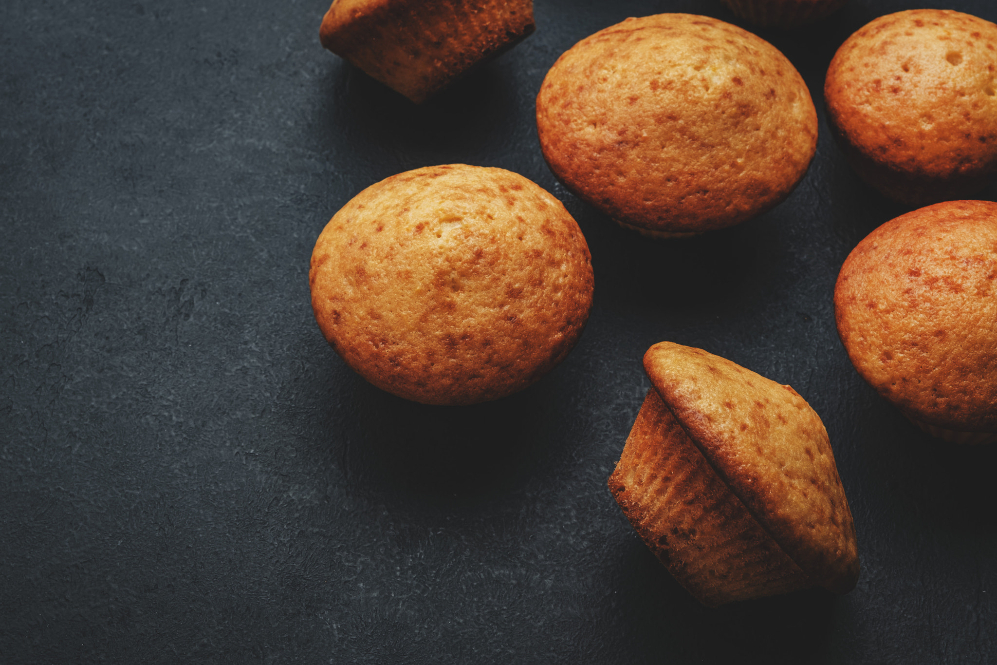 Appetizing orange muffins or cupcakes on black table background, winter homemade pastries, top view