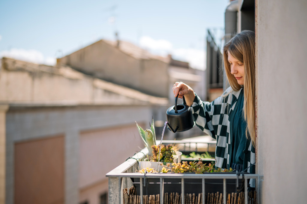 Jeune femme arrosant des plantes sur un balcon par Olha Dobosh sur 500px.com