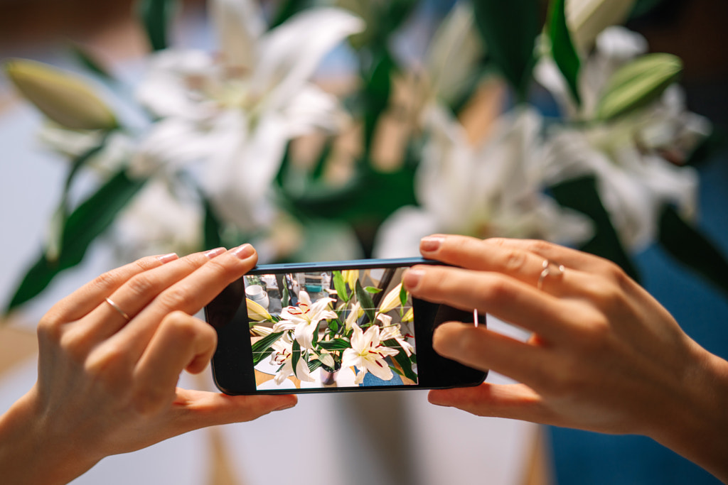 Cropped hands of woman photographing flowers on mobile phone by Olha Dobosh on 500px.com