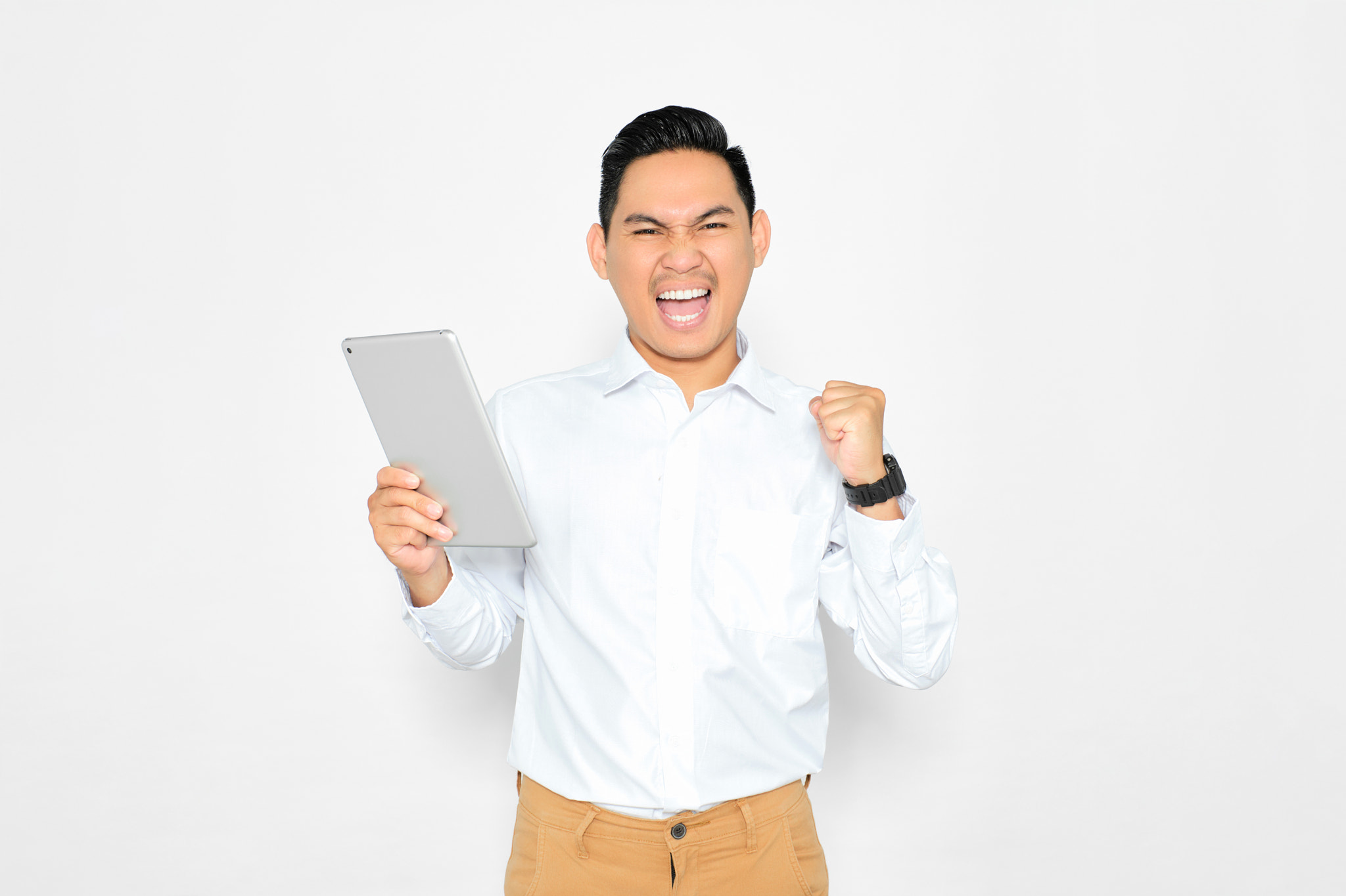 Excited young Asian man using digital tablet, celebrating success, raising fist, trading online