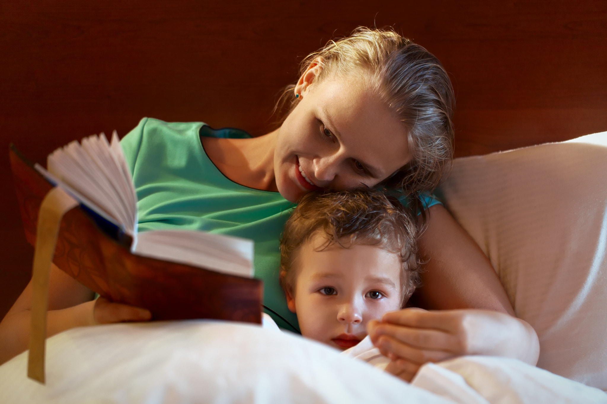 Young mother reading to her child in bed