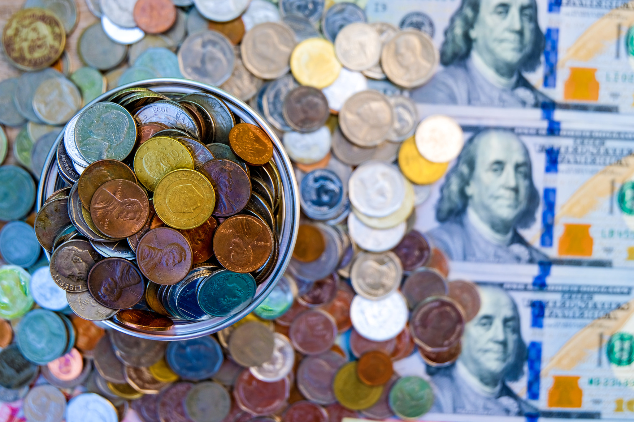 Close up heap of coins lay on US dollar and Chinese Yuan banknote.