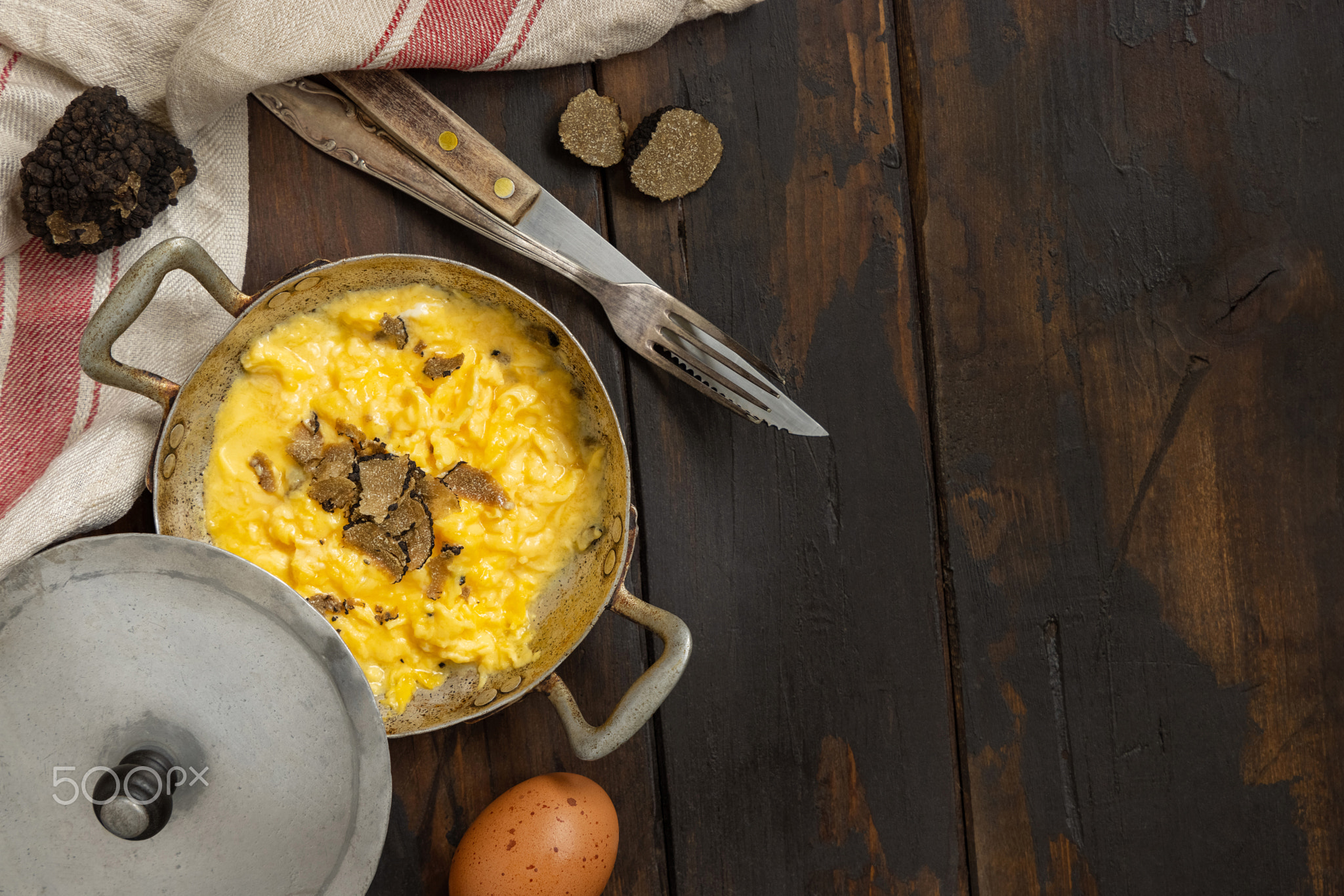 Scrambled eggs with fresh black truffles from Italy served in a frying pan top view, copy space