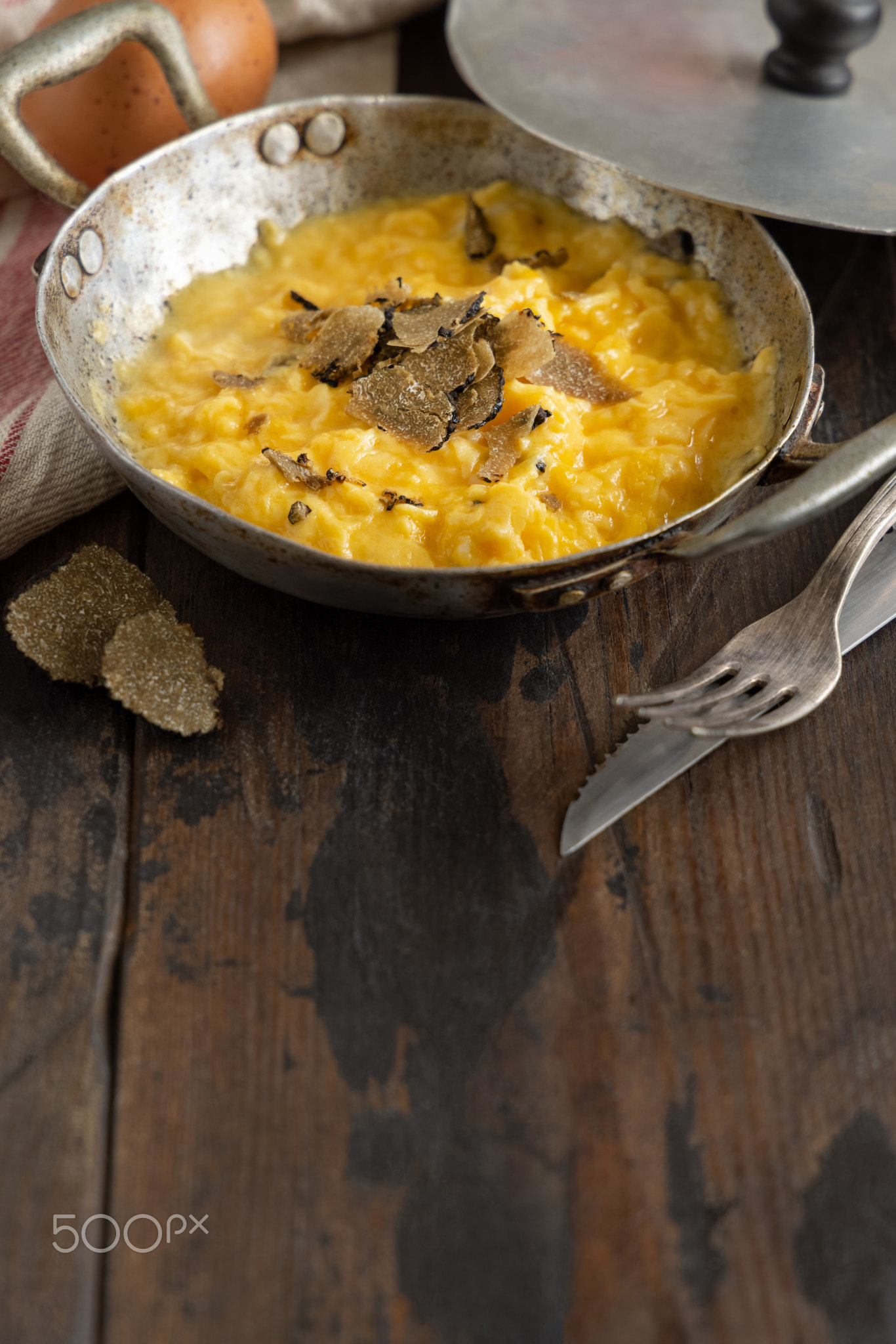 Scrambled eggs with fresh black truffles from Italy served in a frying pan, close up, copy space