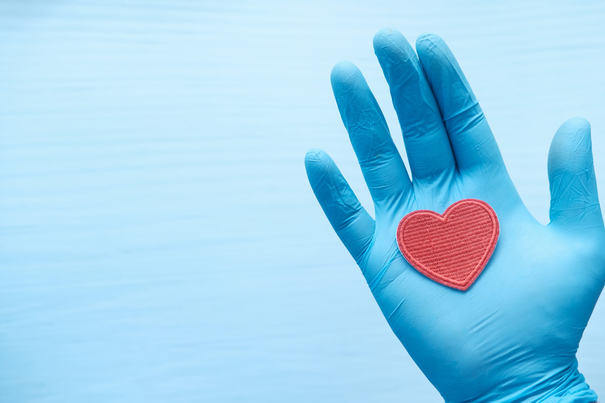 man hand in protective gloves holding red heart