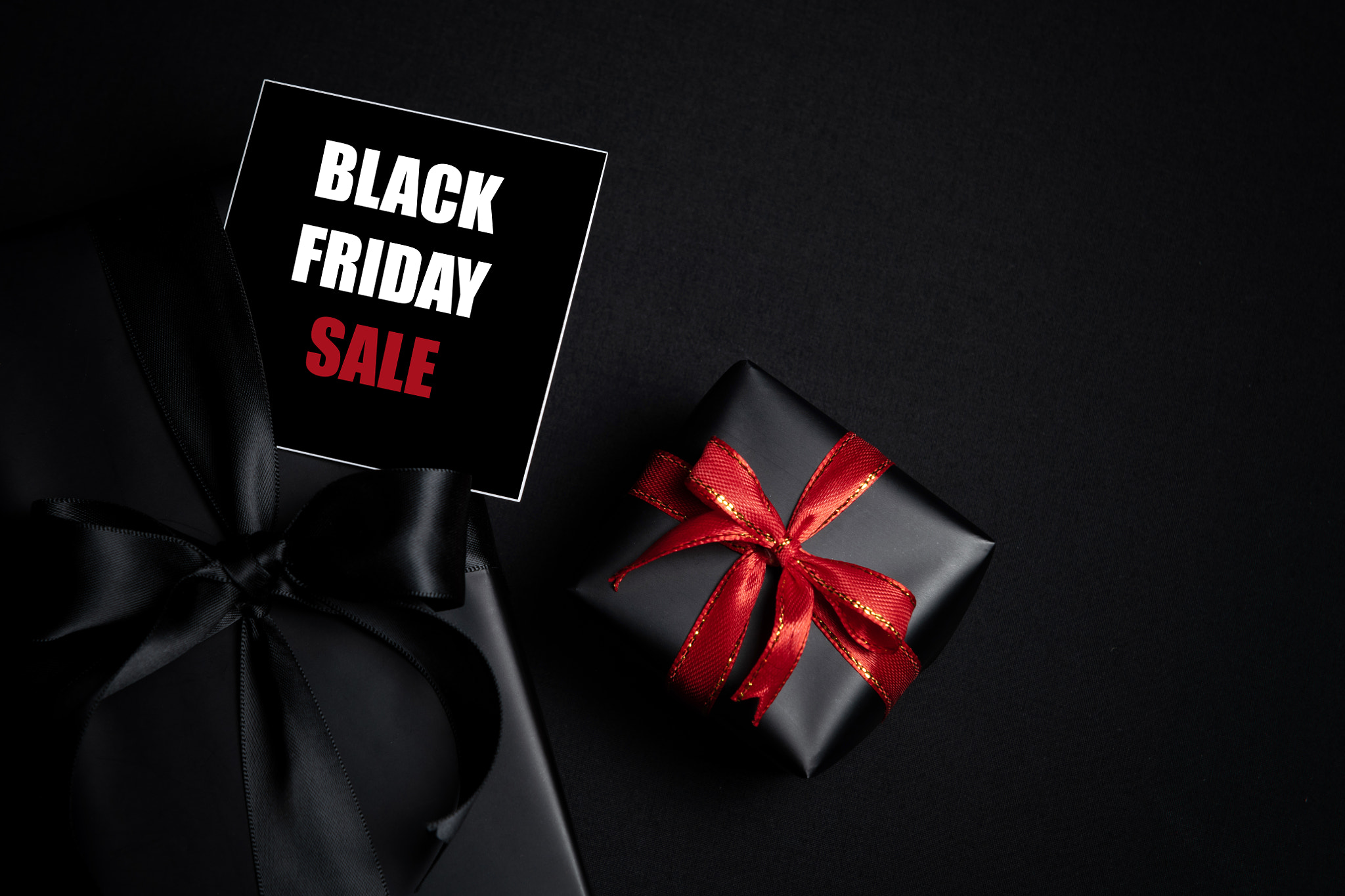 Top view of Black Friday Sale text with black gift box isolated on black background.
