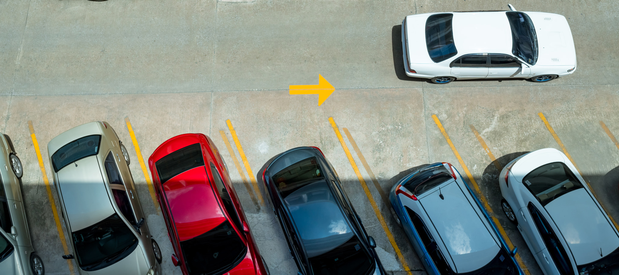 Top view of car parked at concrete car parking lot with yellow line of traffic sign on the street. A