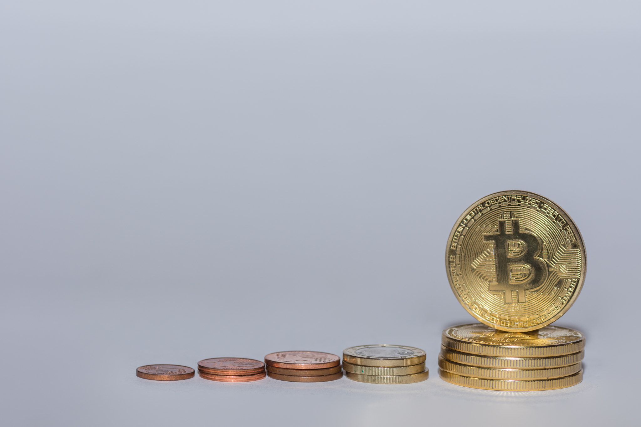 euro coins and bitcoins from crypto currency stacked in a row with gray