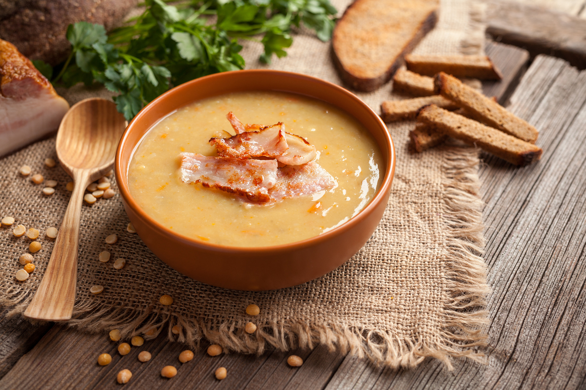 Traditional german homemade pea soup recipe with bacon and croutons in clay dish on vintage wooden t