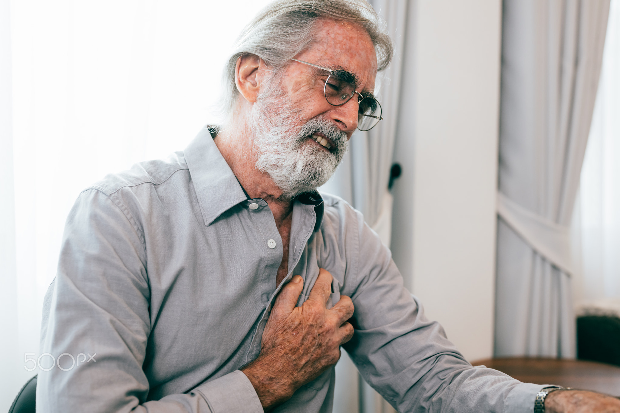 Senior man holding hand on chest and suffering from heart problem at