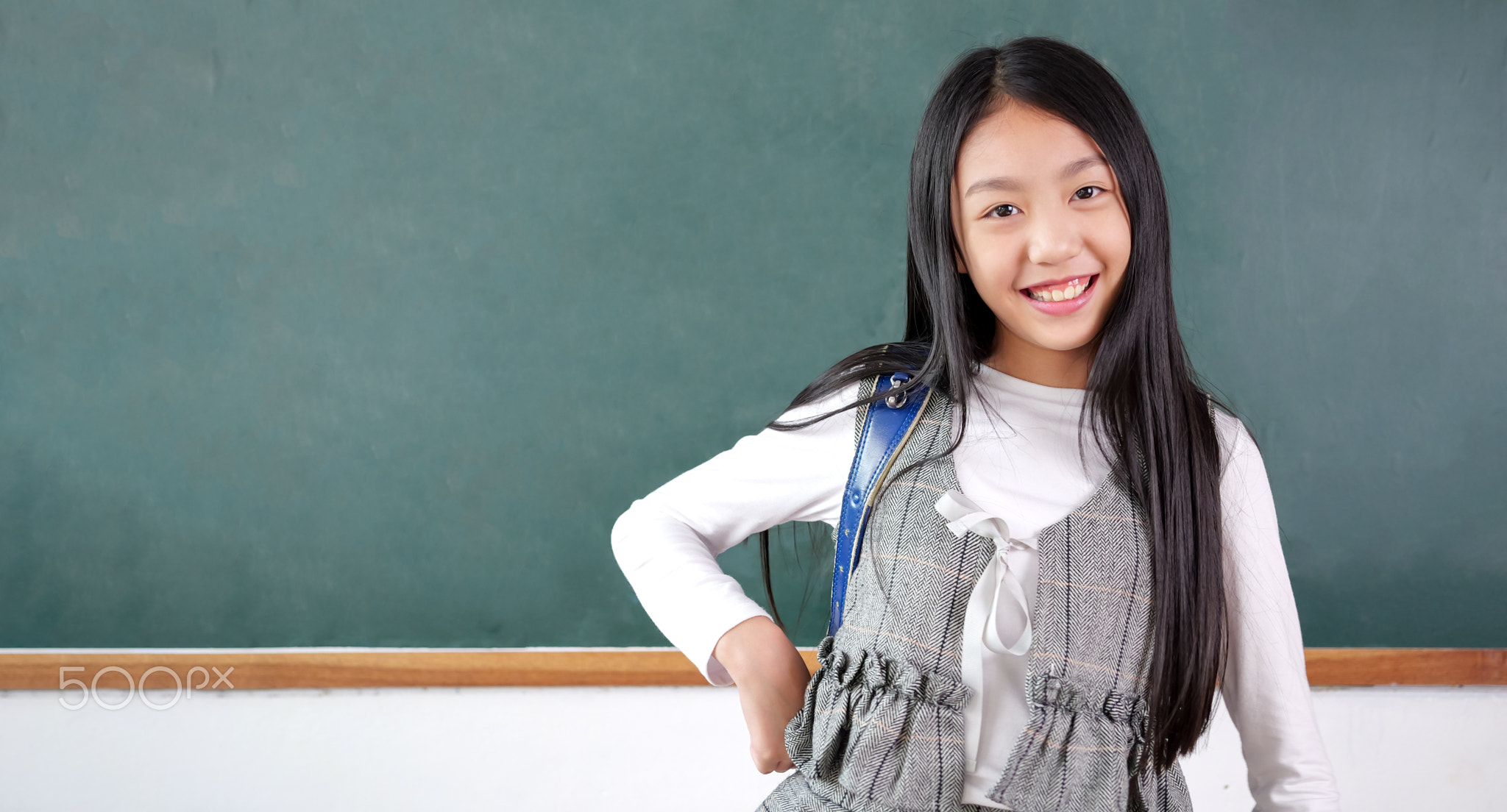 Happy schoolgirl with schoolbag portrait in the classroom