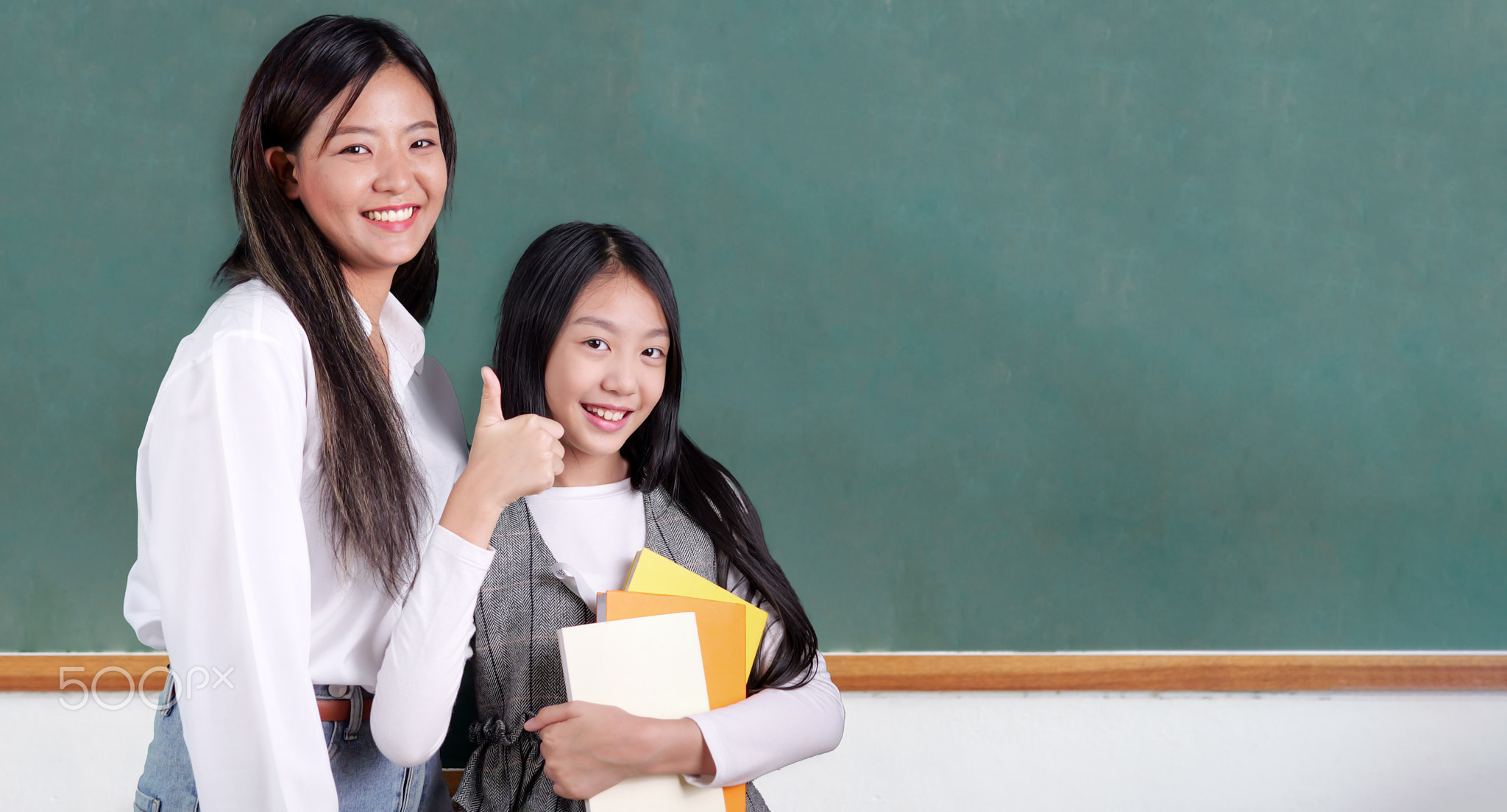 Happy student studying with teacher in classroom at school