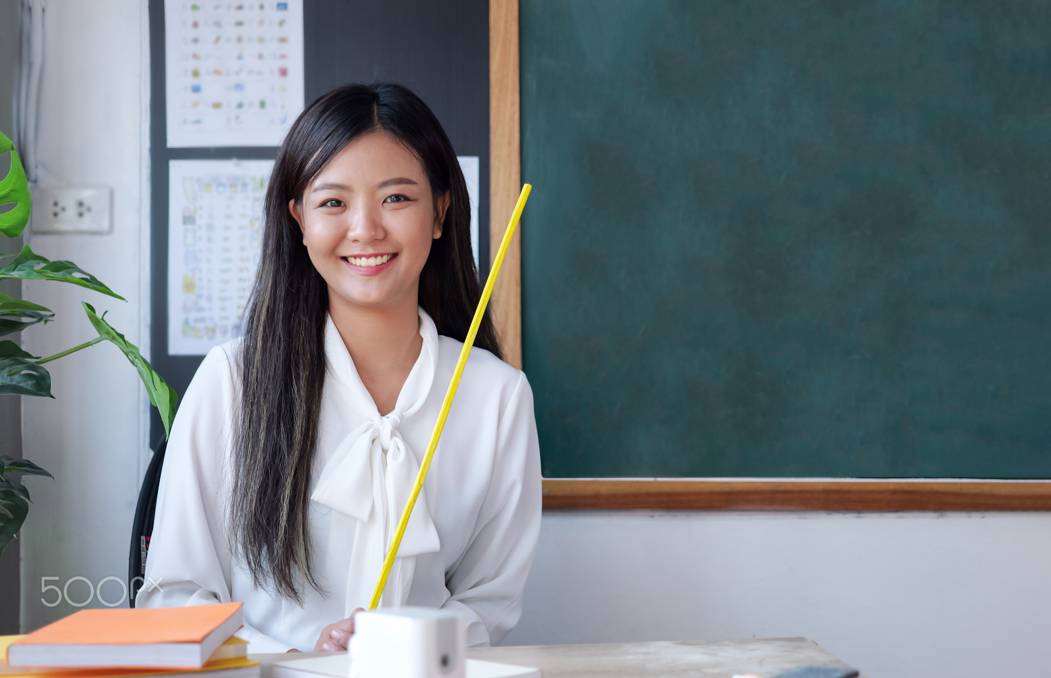 Teacher sitting near backboard posing to camera with smile