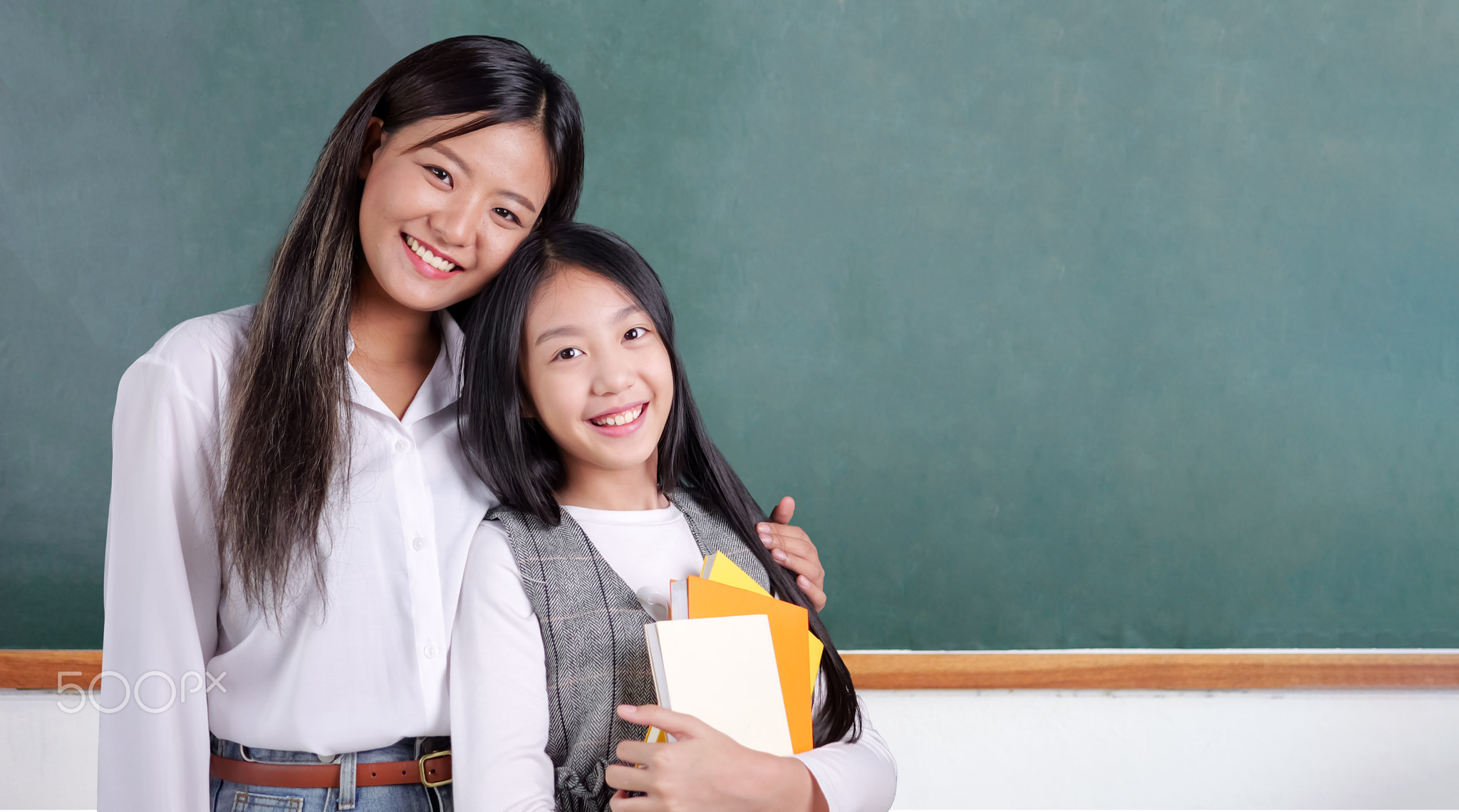 Happy student studying with teacher in classroom at school