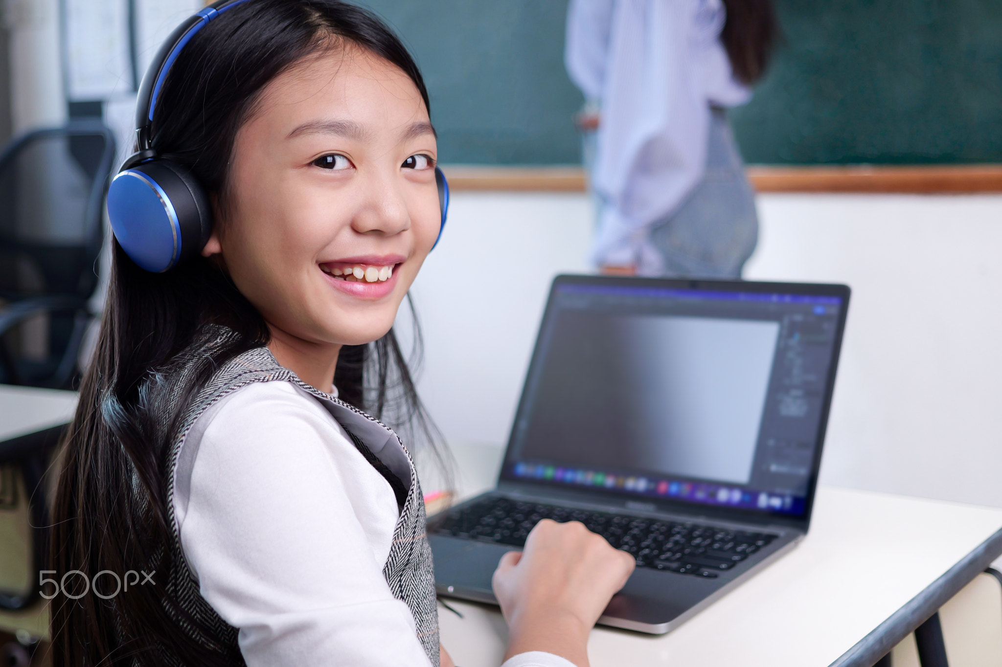 Happy student studying with teacher in classroom at school