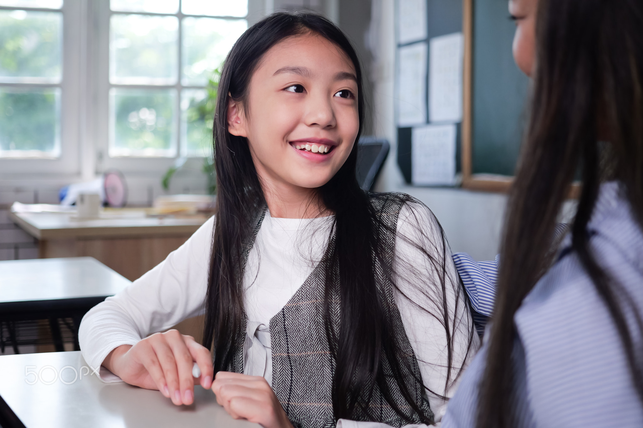 Happy student studying with teacher in classroom at school