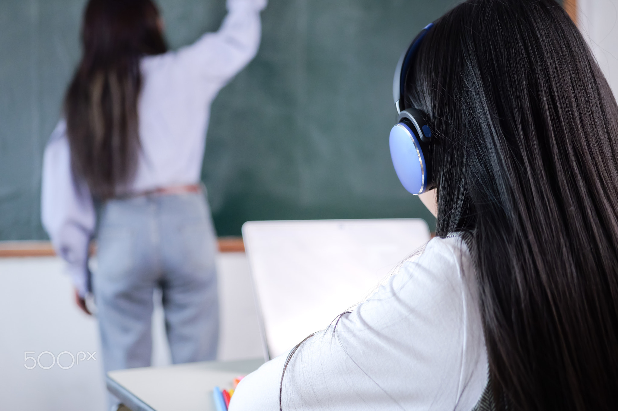 Happy student studying with teacher in classroom at school