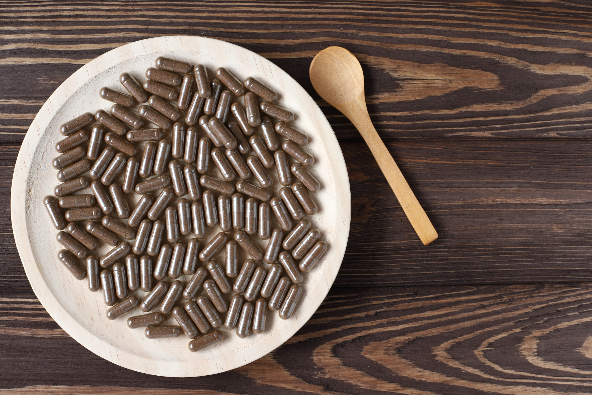 Brown pills on plate, vitamons food supplement: Pills and vitamins on wooden plate, capsules to eat