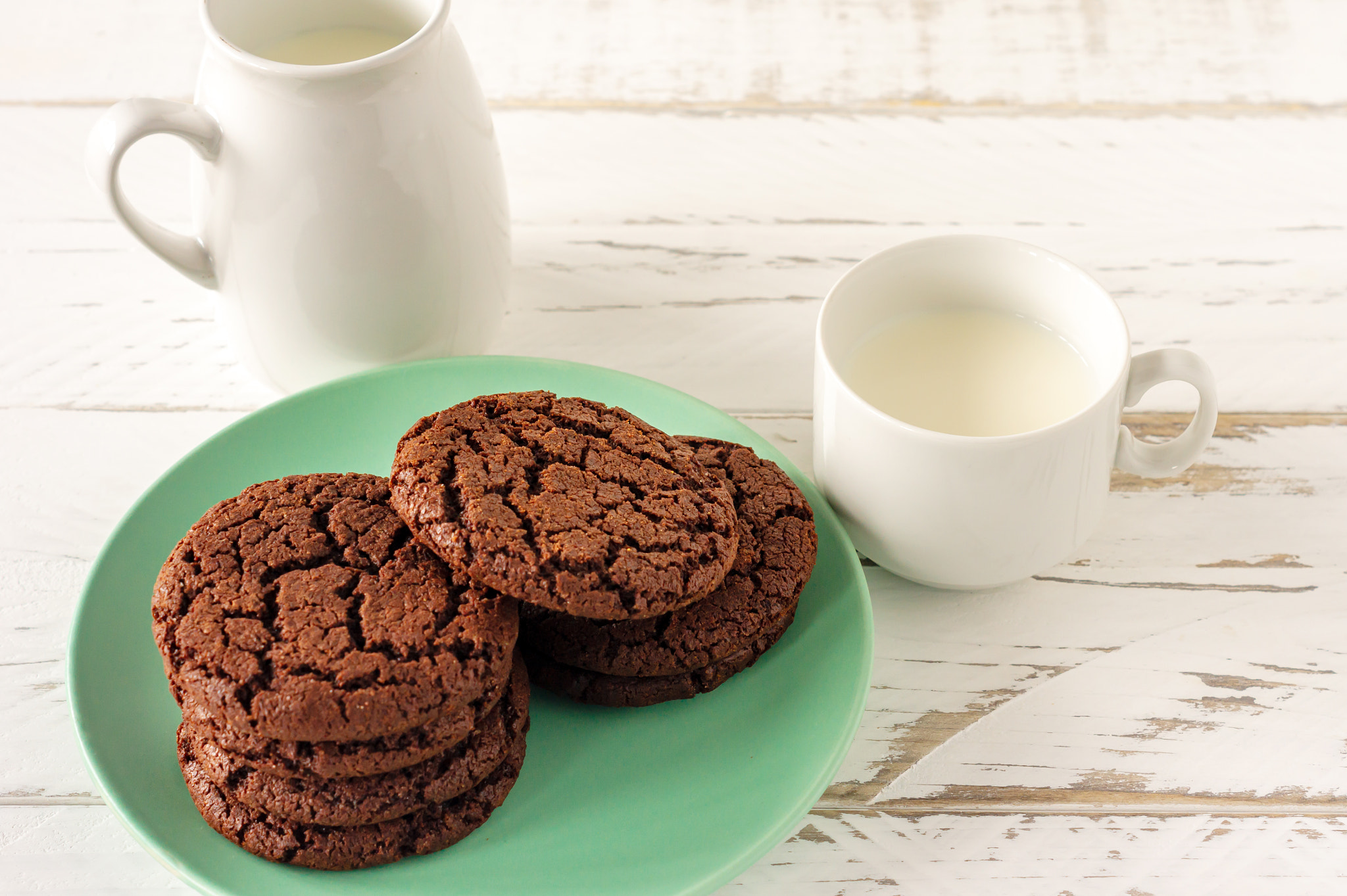 Chocolate cookies for breakfast with a glass of milk on a white wooden table.