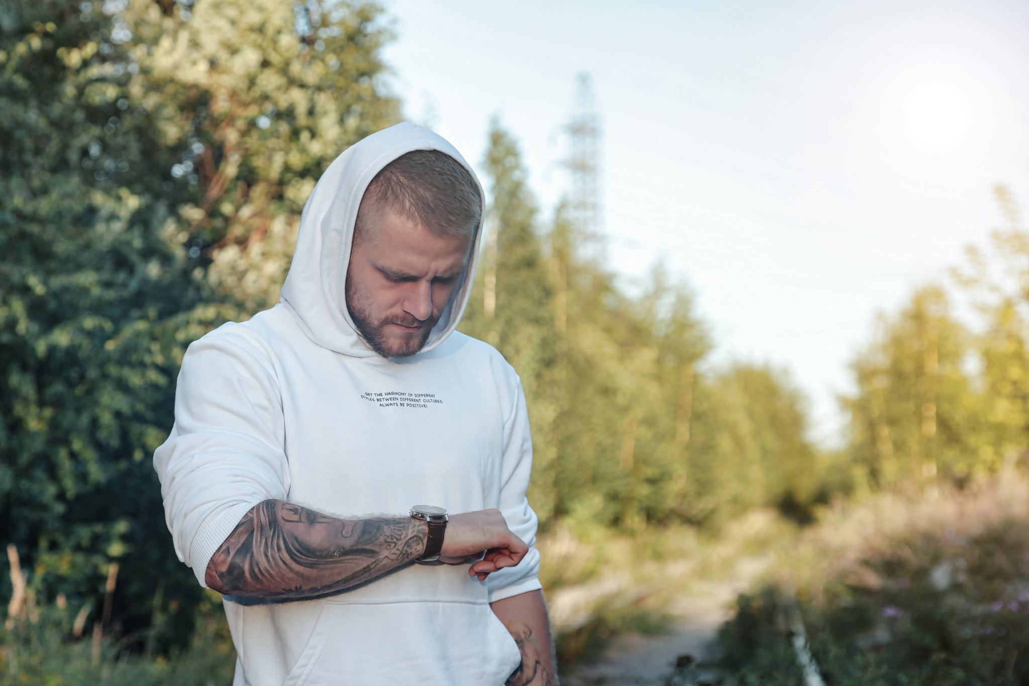 Bearded jewish guy in white jacket in forest, looking at clock what time is it