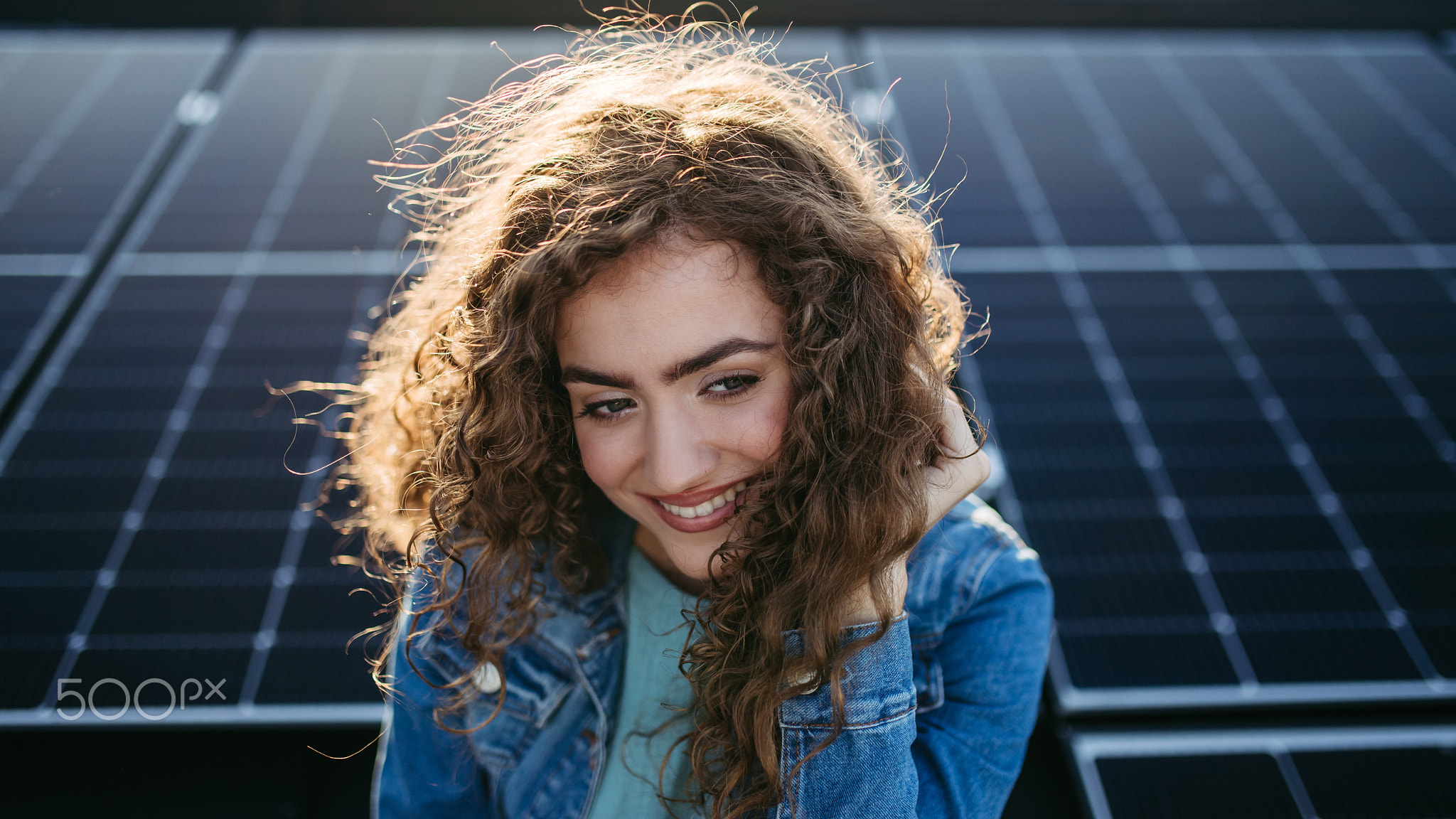 Portrait of young woman on roof with solar panels.