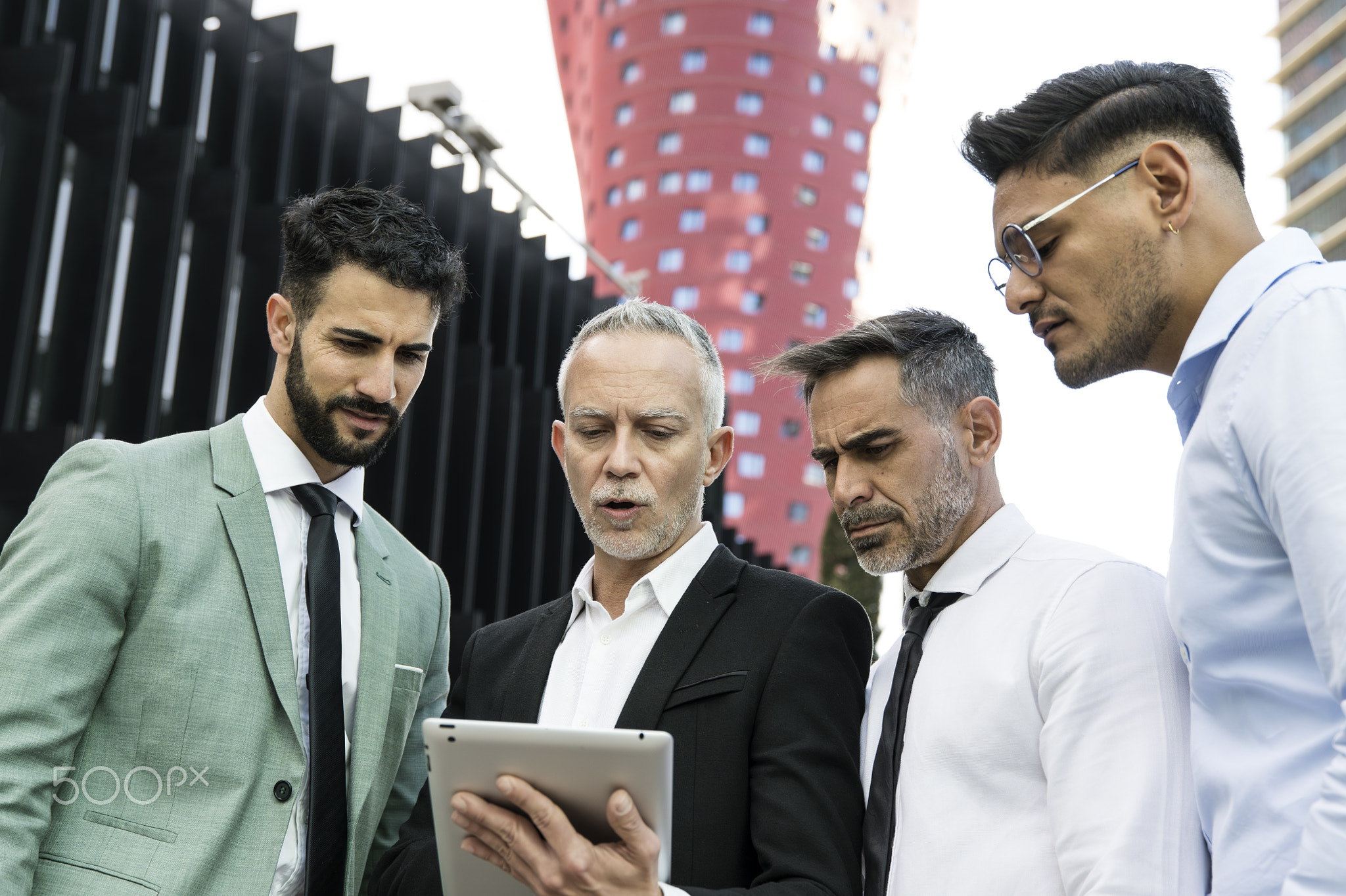 Diverse group of businessman checking a tablet in the street. Senior