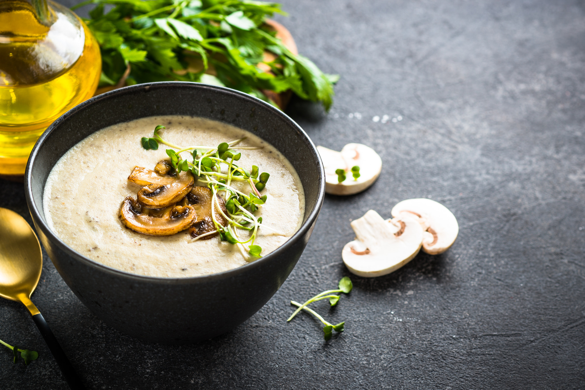 Mushroom Soup in craft bowl on dark stone table.