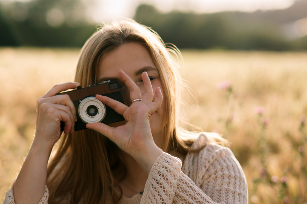 אישה צעירה מצלמת עם מצלמה בשדה מאת Olha Dobosh ב-500px.com