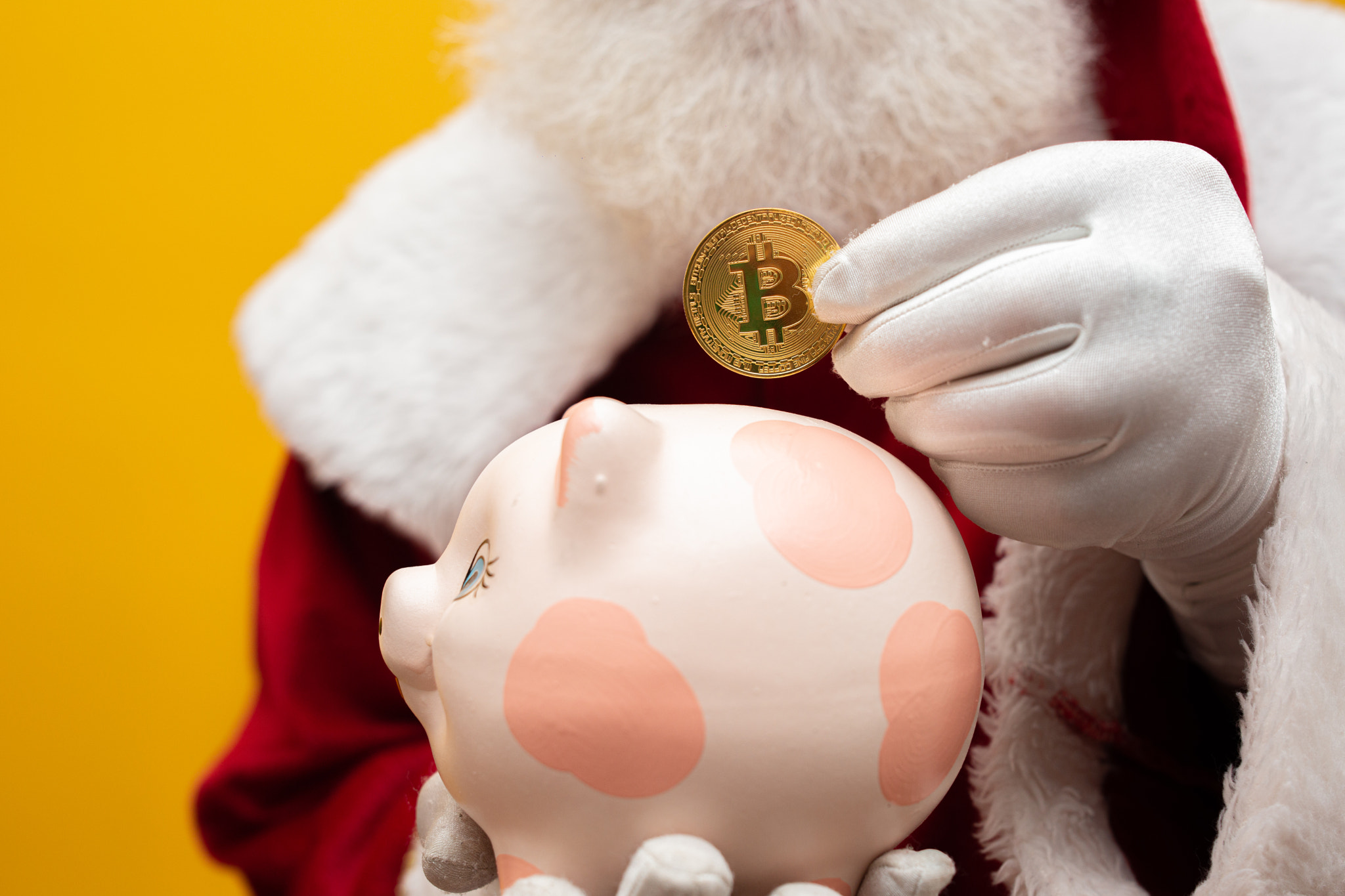 Santa Claus putting coin into a ceramic piggy bank. Savings concept for the end of the year. Spendin