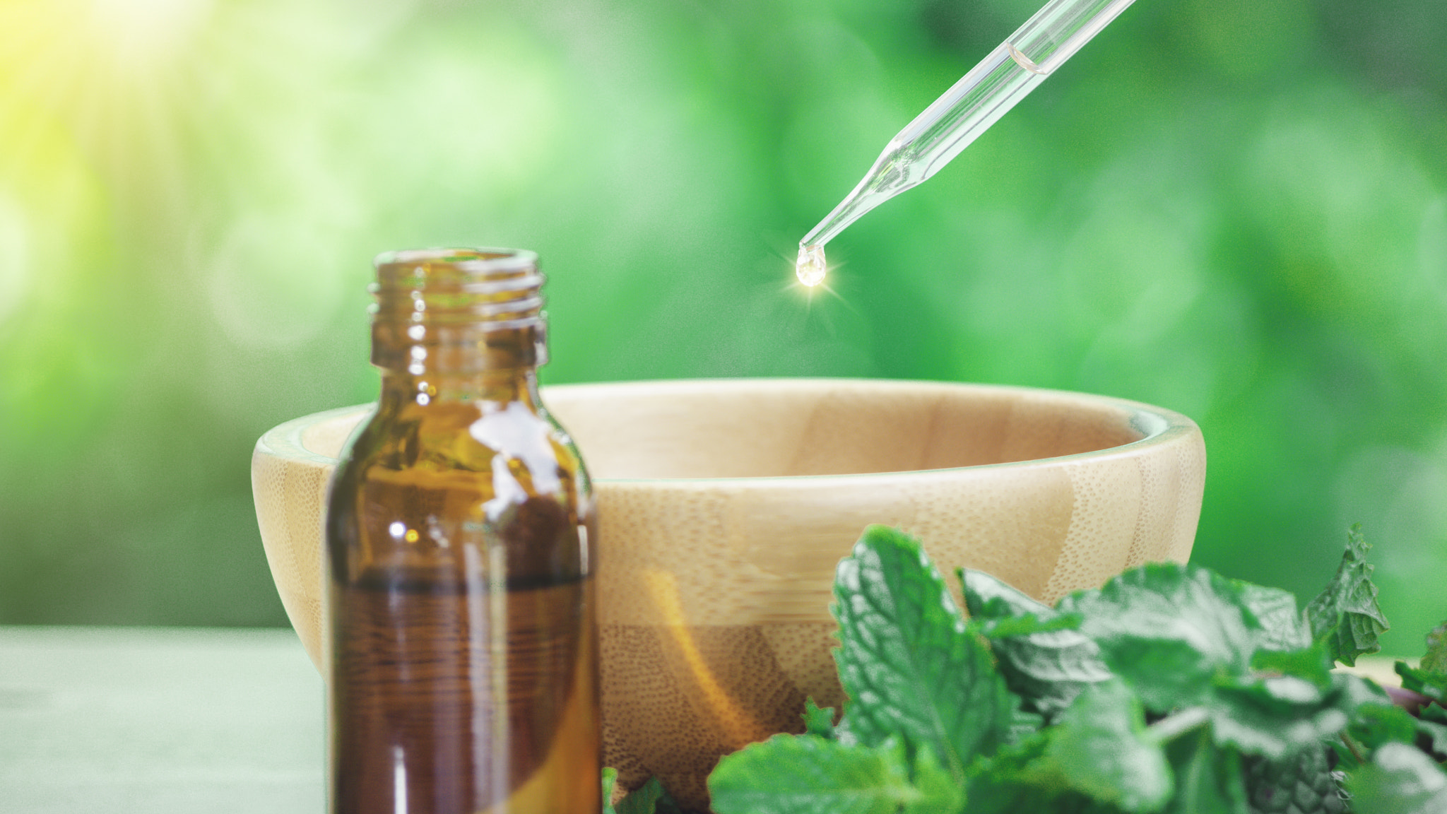 The peppermint extract in small bottle near peppermint leaf on wooden table. The essential oil falli