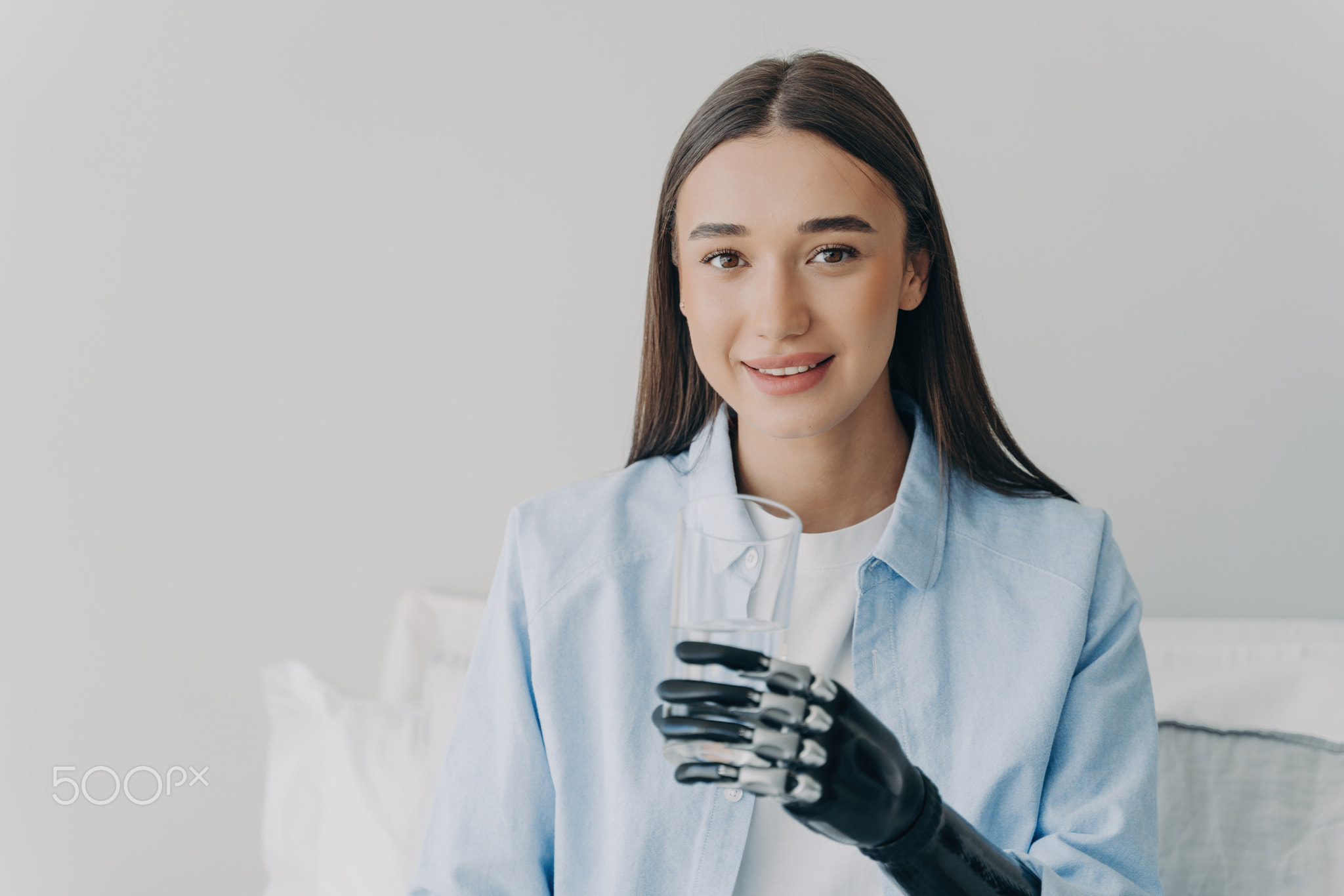 Disabled girl grasps a glass with myoelectric hand. High technology prosthesis.