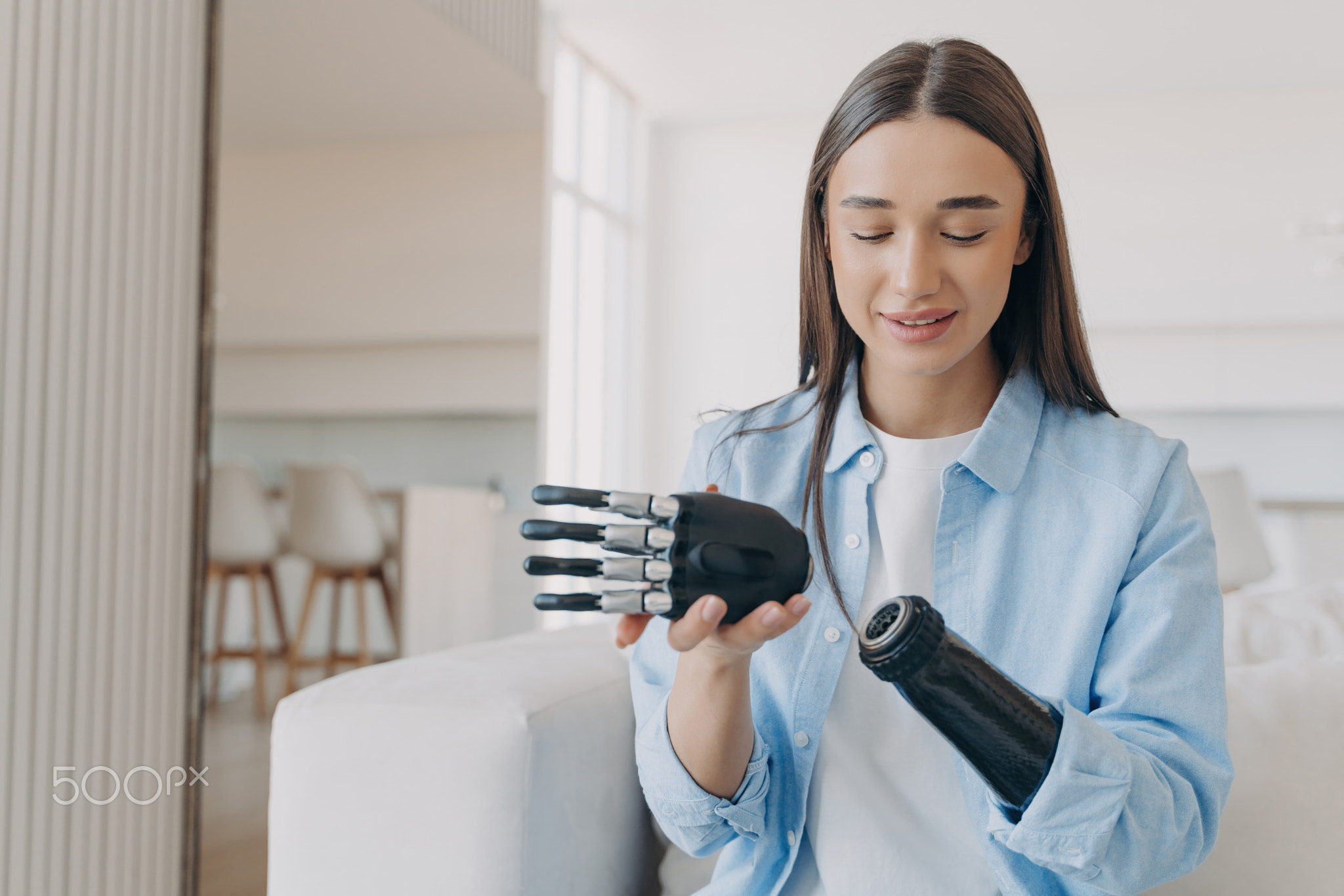 Disabled young woman is assembling bionic arm with hand. Prosthesis is connecting in wrist joint.