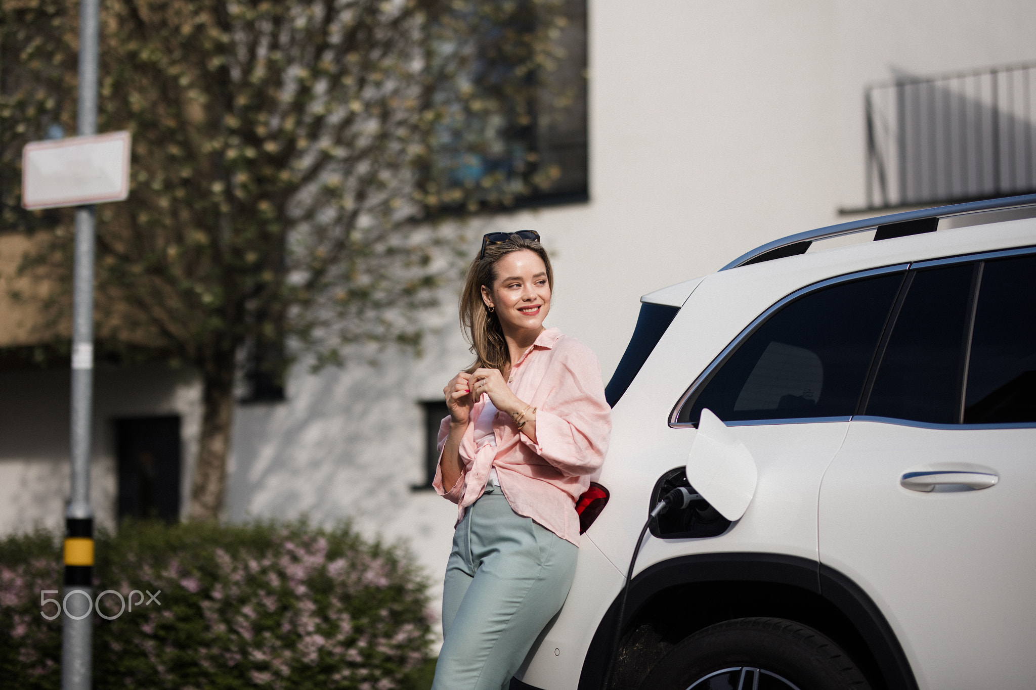 Young woman charging her electric car in home, sustainable and economic transportation concept.