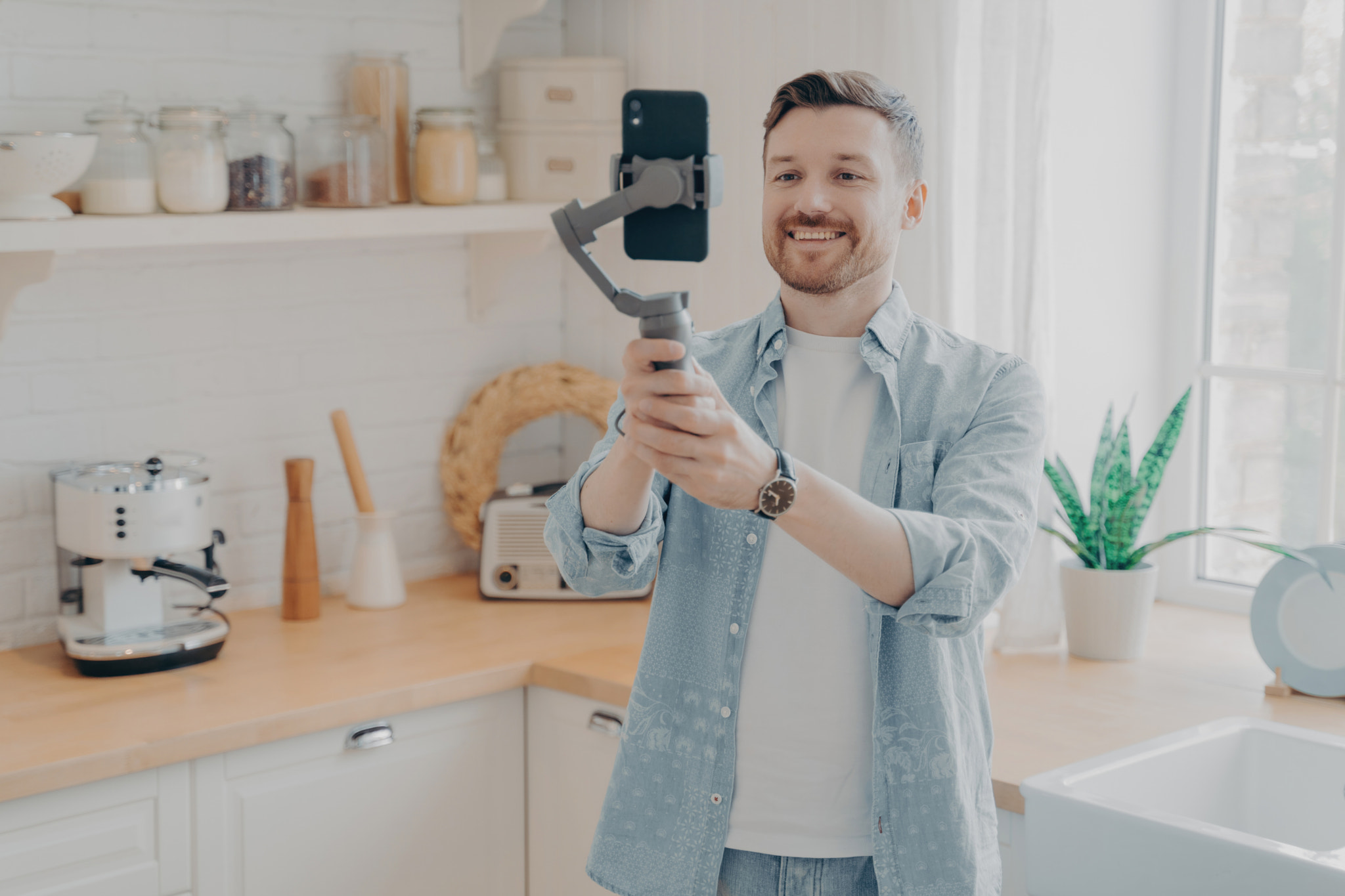 Young man blogger recording video blog with mobile phone at home