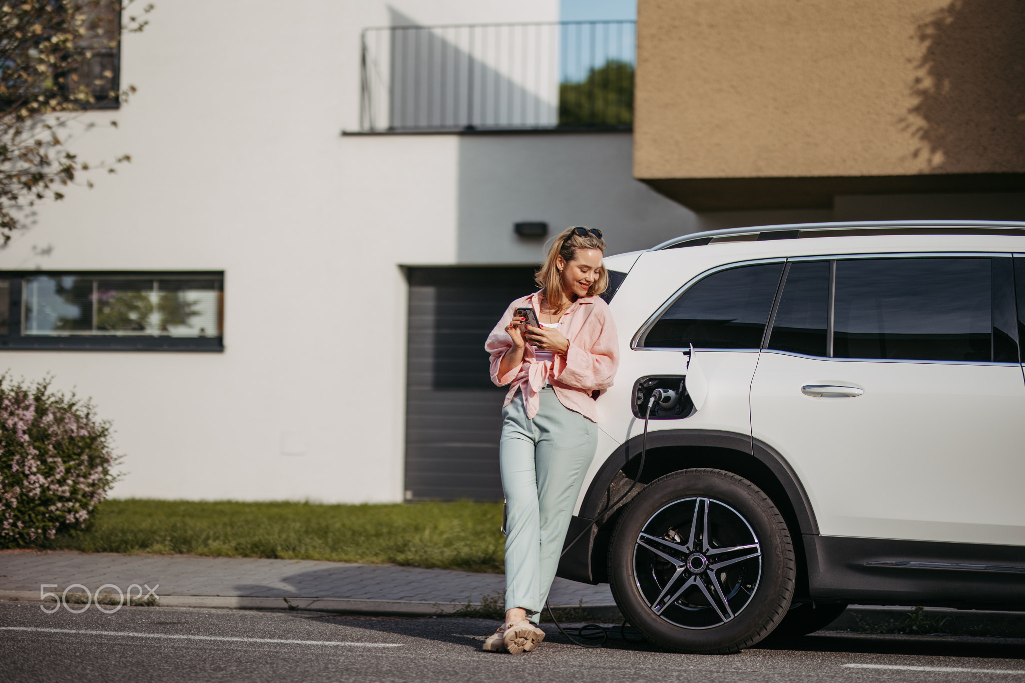 Young woman charging her electric car in home, sustainable and economic transportation concept.