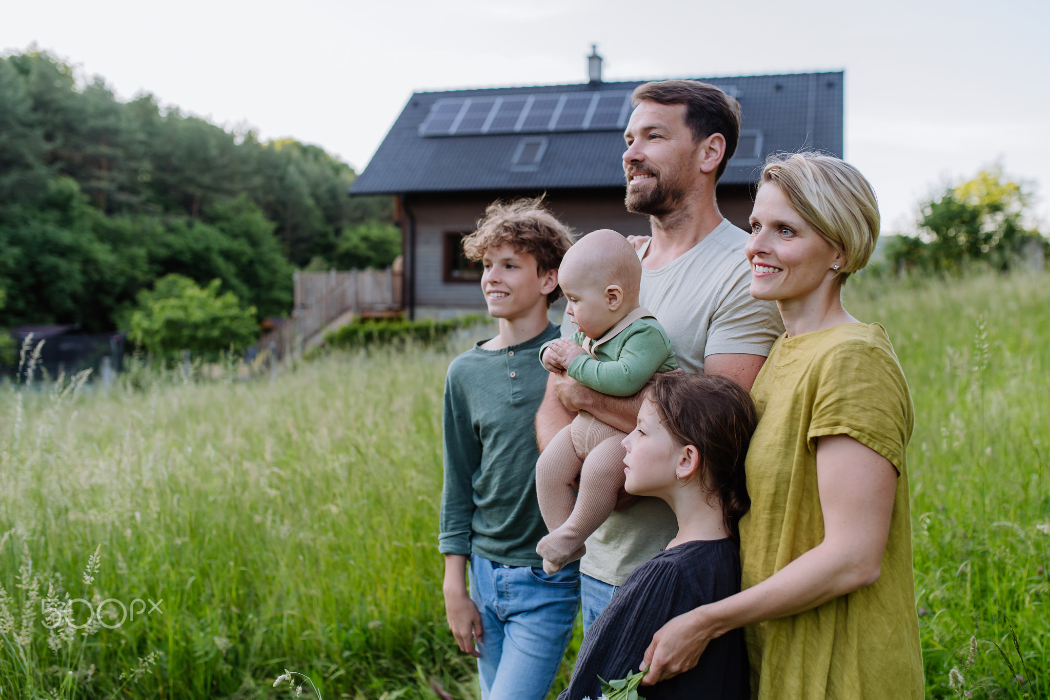 Happy family near their house with solar panels. Alternative energy, saving resources and