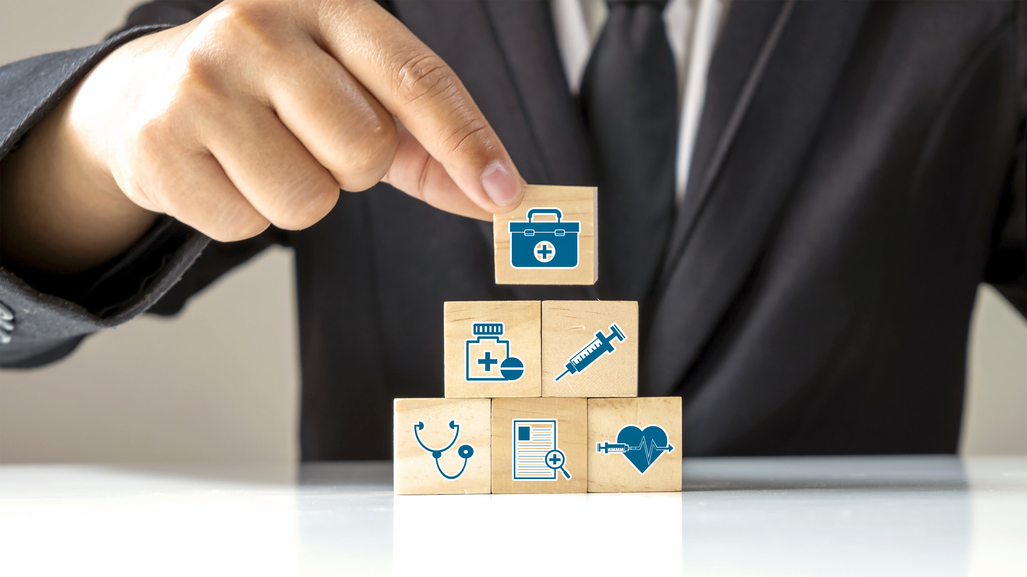 The medical icon on wooden cube block and male businessman hand choosing medicine bag icon on wooden