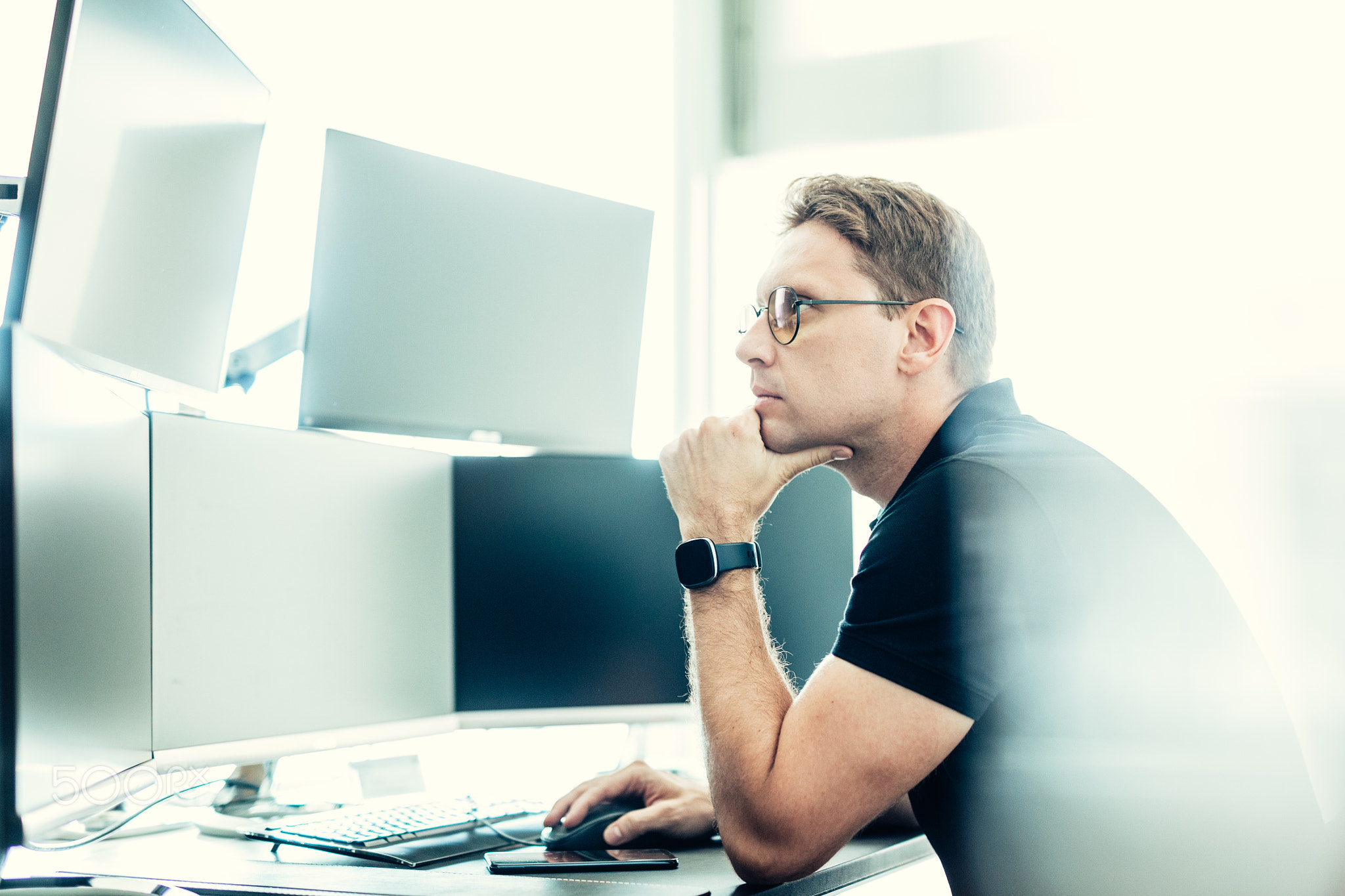 Stock broker trading online watching charts and data analyses on multiple computer screens.